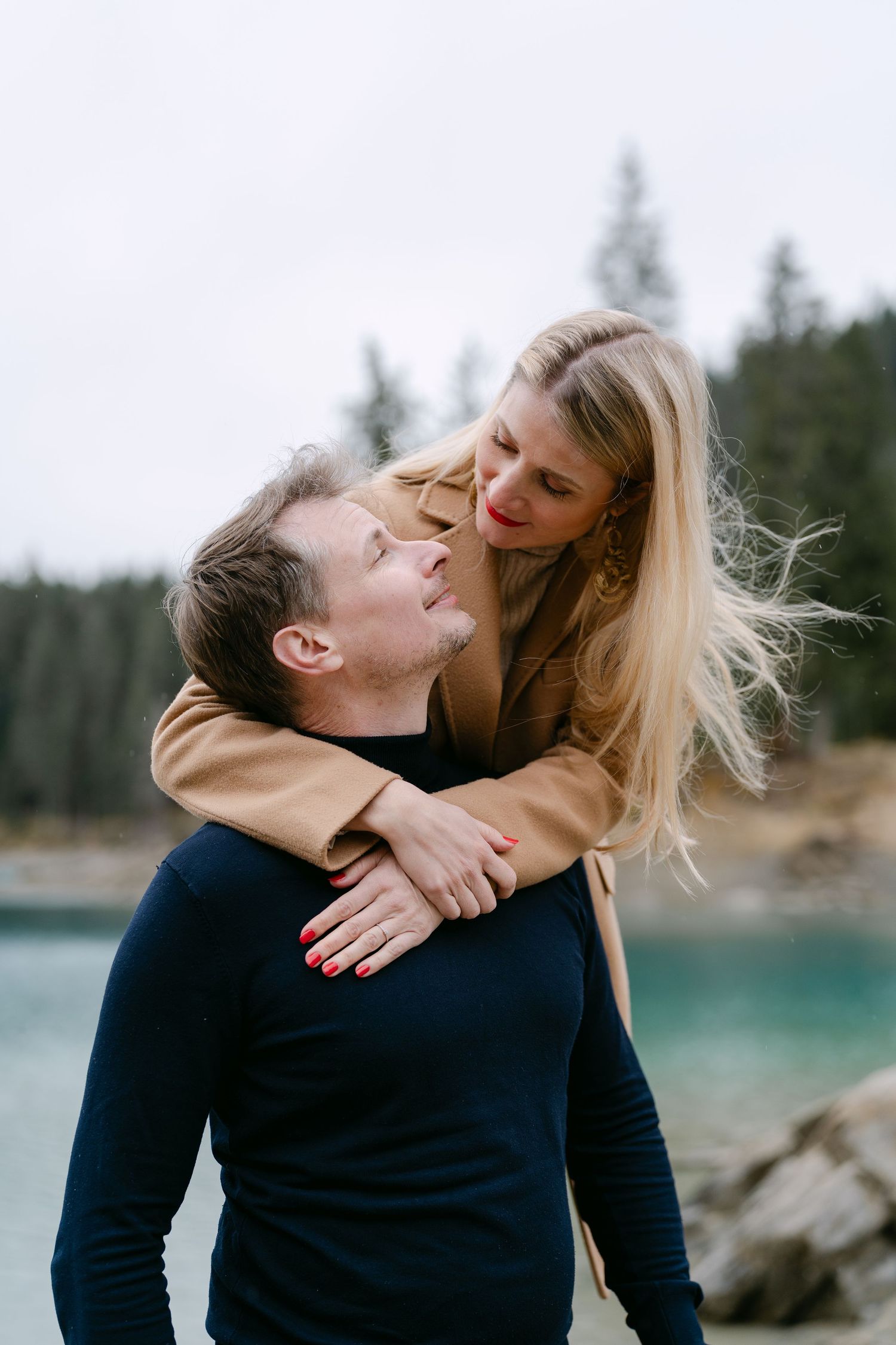 A playful couple shares a joyful moment by a scenic mountain lake.