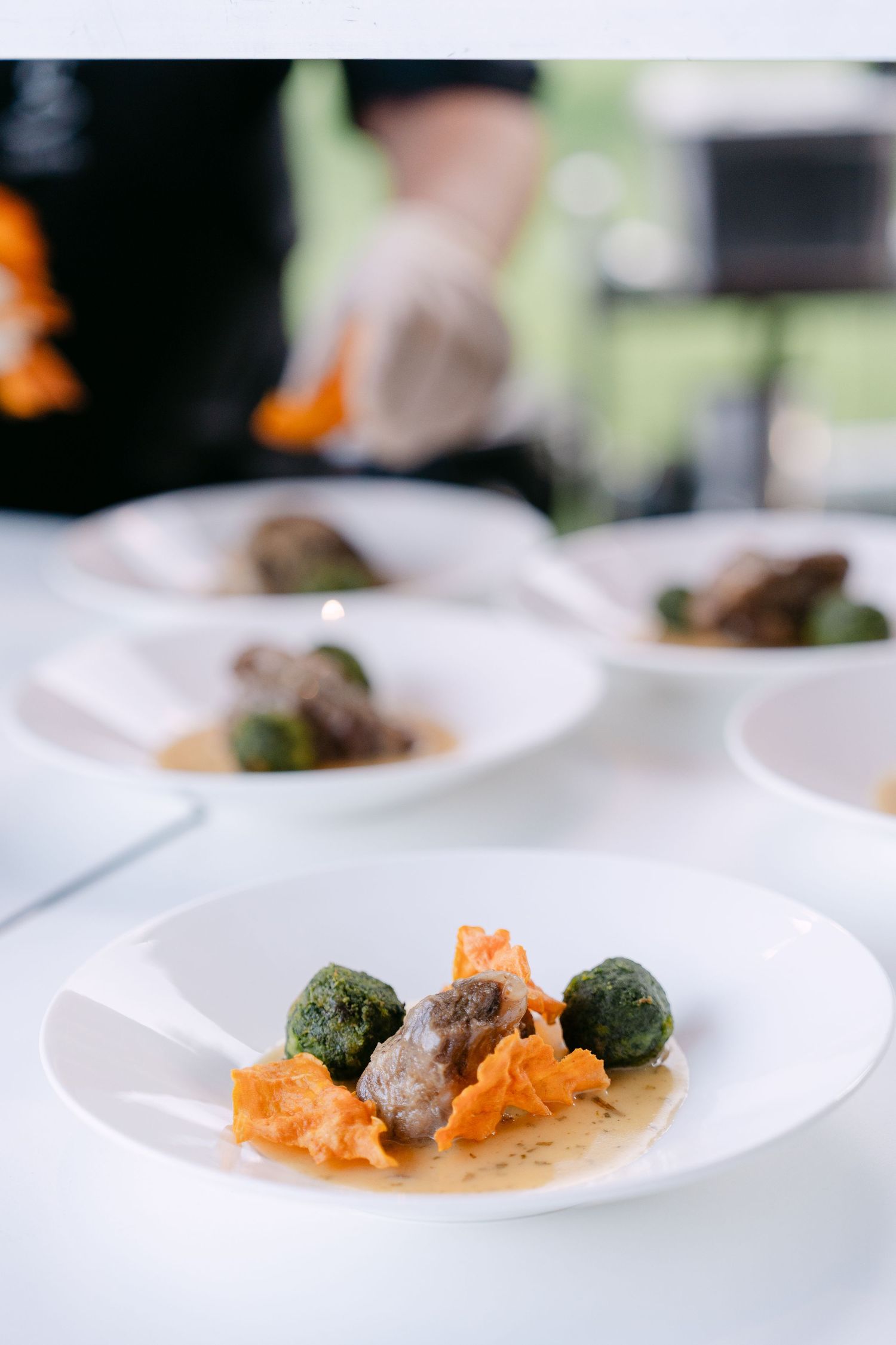 Plated appetizers with salmon and green garnish on white dishes.