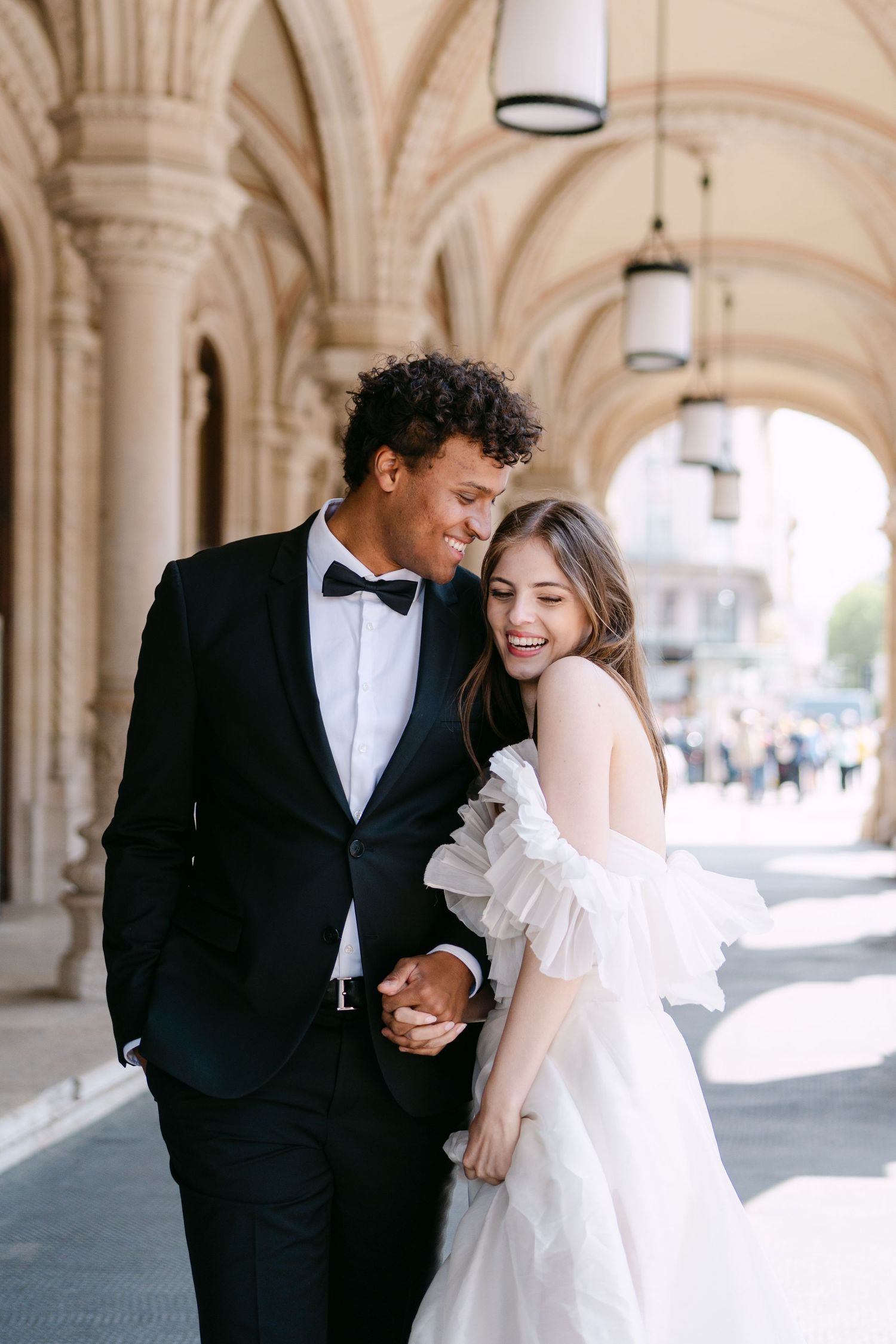 Wedding couple shares intimate moments under ornate arched colonnade.