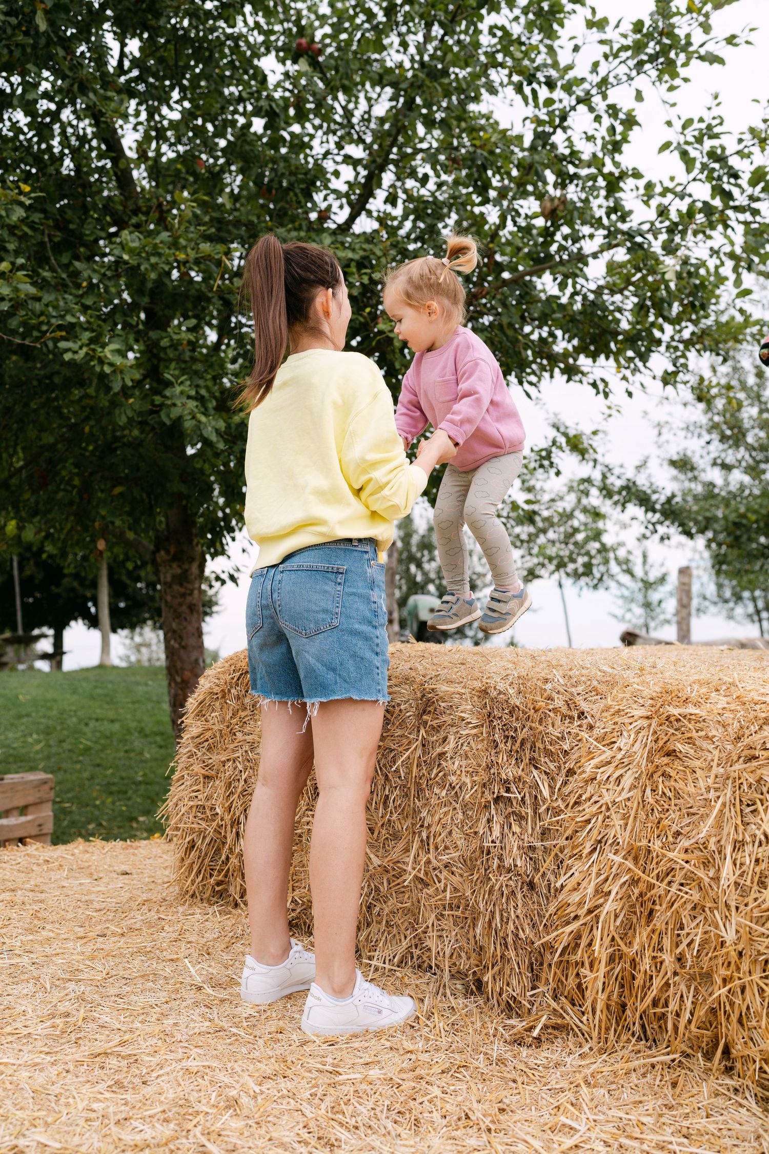 Candid moments captured on hay bales in a sunny outdoor setting.