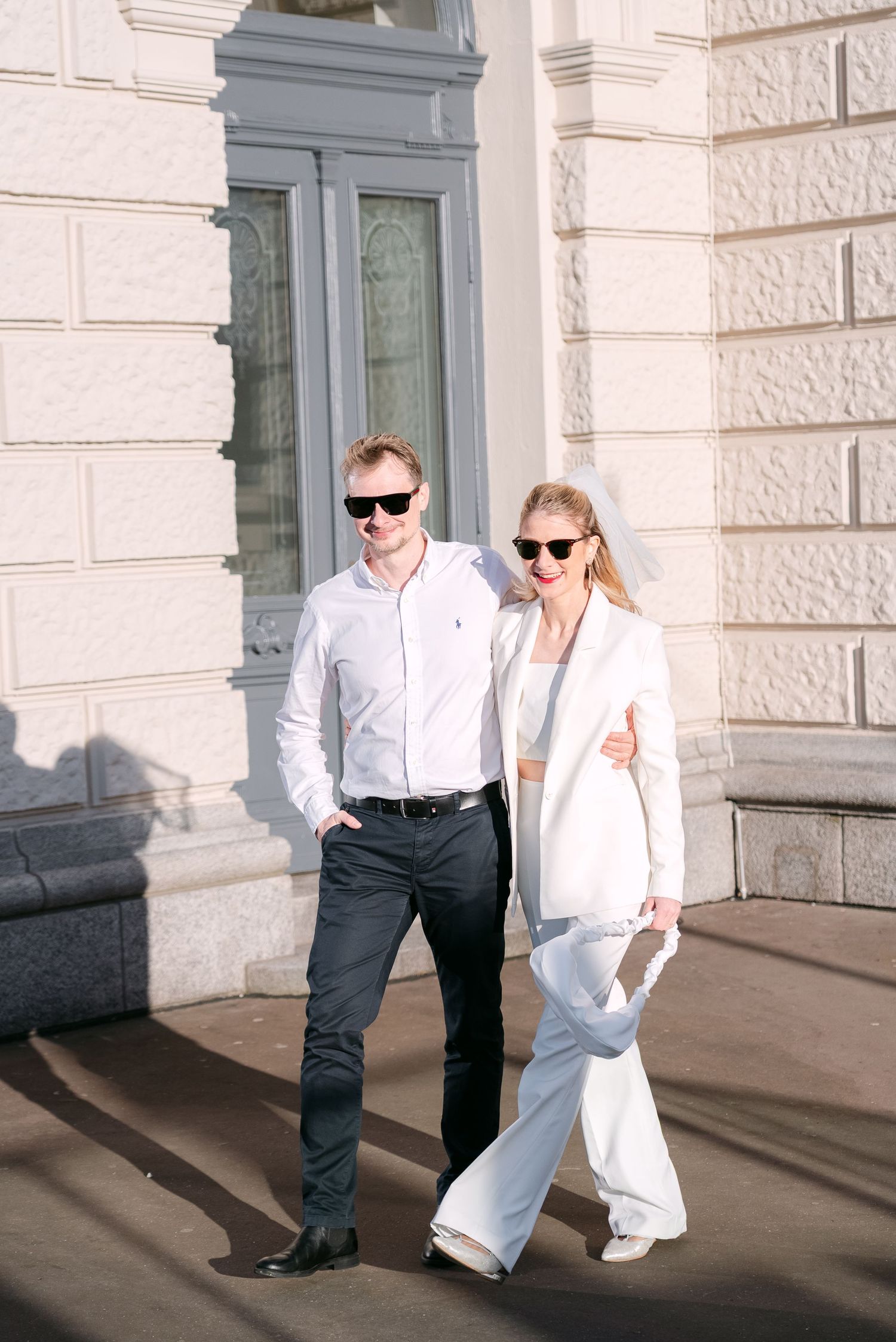 Stylish couple in contrasting black and white outfits posing against a classical building facade.