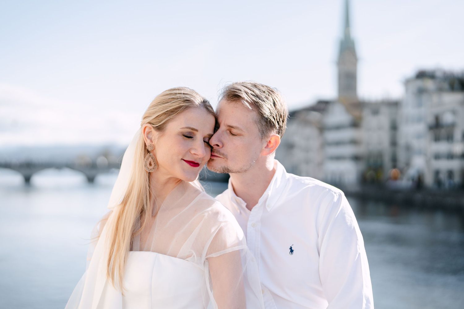 Intimate waterfront wedding portraits with city skyline and church spires in soft focus.