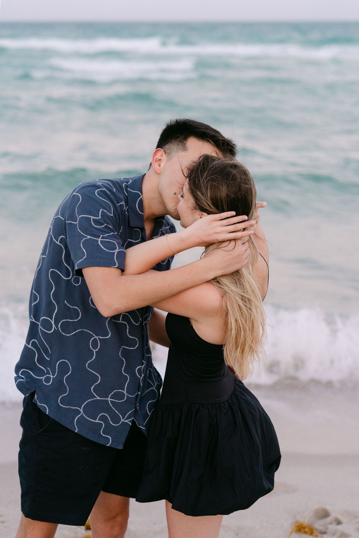 A couple shares an intimate moment while embracing on a beach during a photo session.