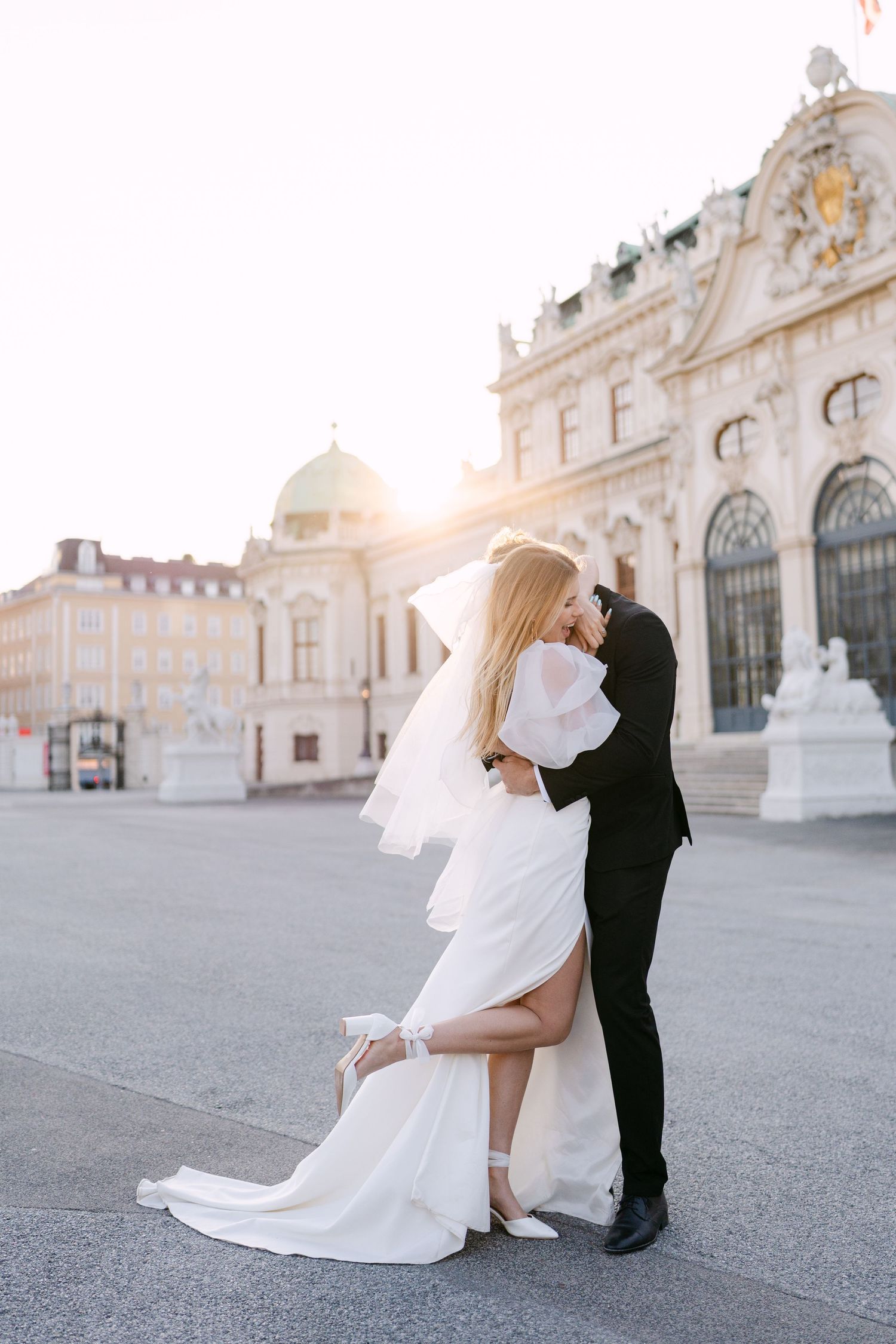 Romantic dance poses captured in front of historic palace at sunset.