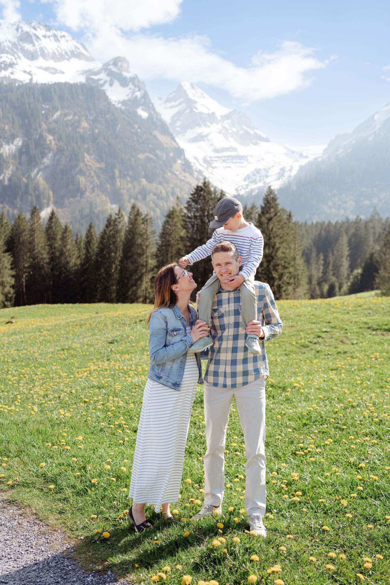Family enjoying a spring day in an alpine meadow with snow-capped mountains in the background.