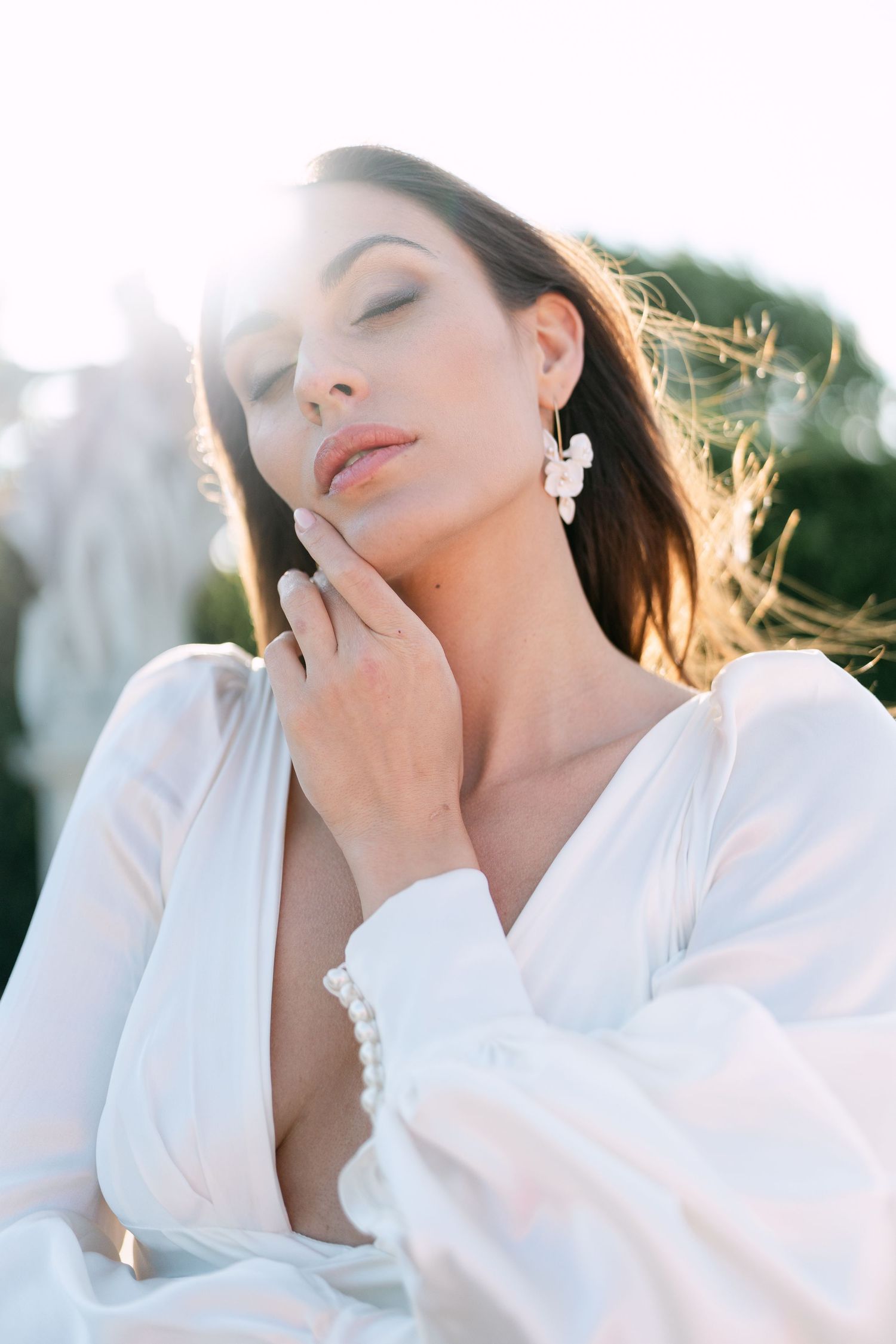 Dreamy bridal portraits capture soft sunlit moments in white flowing gown.