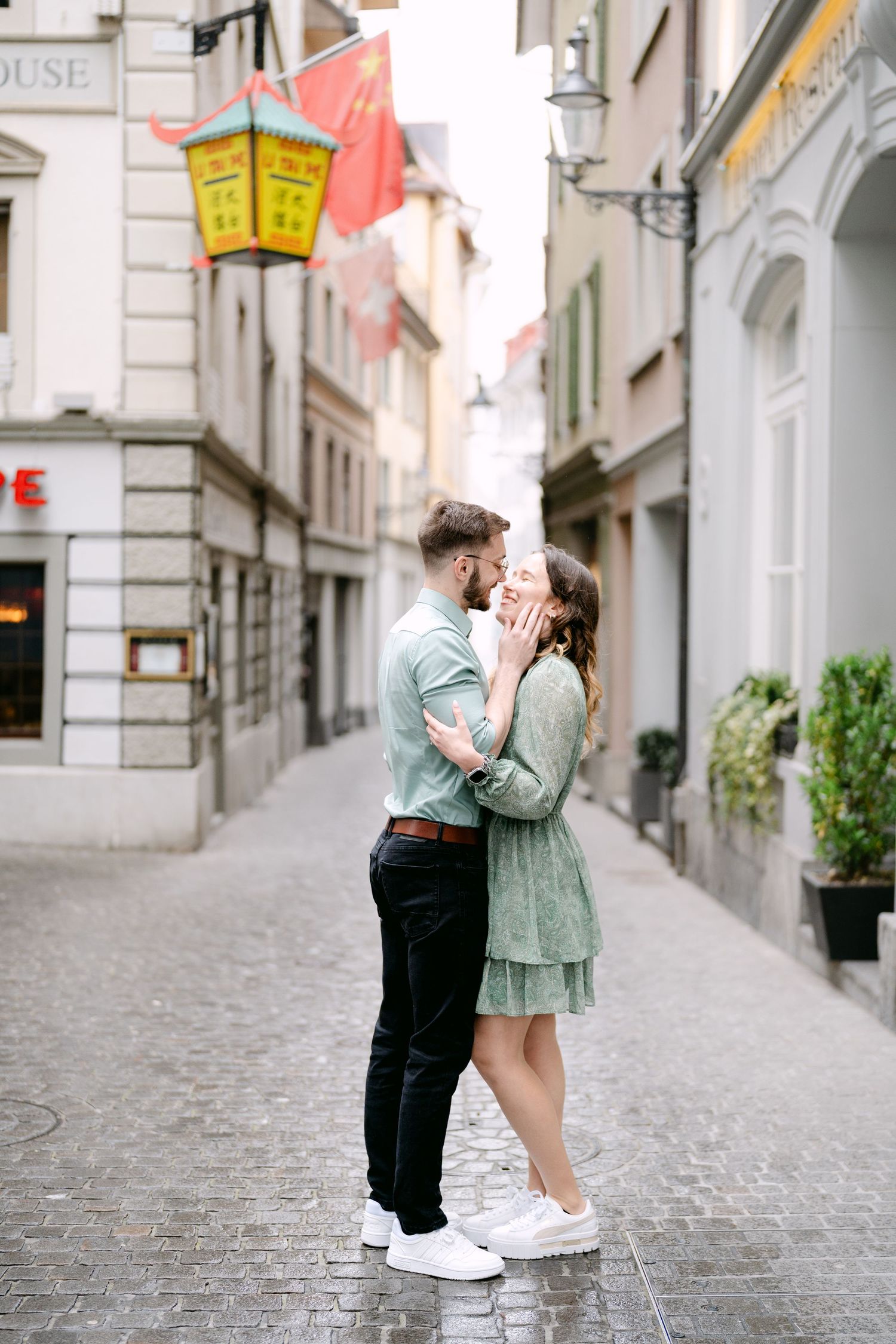 A couple shares a tender moment on a charming cobblestone street in Europe.