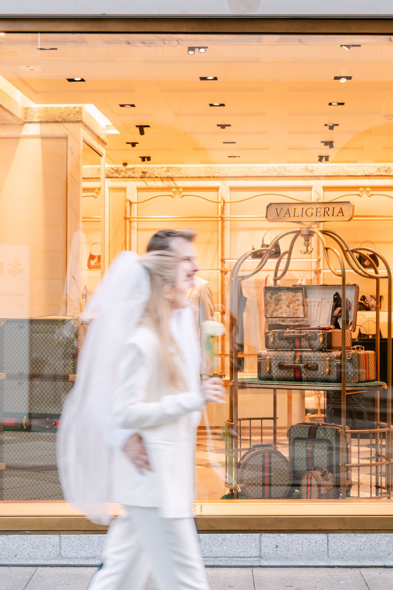 Motion blur sequence showing figures in white moving past a brightly lit storefront.
