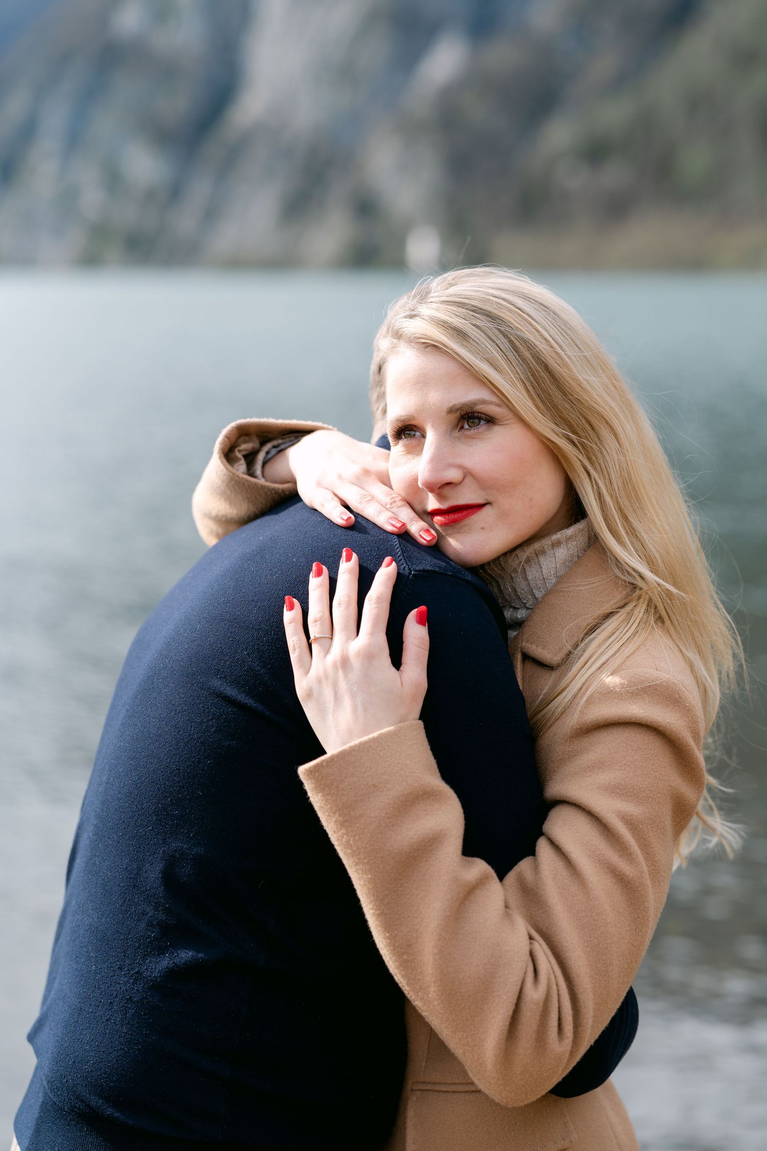 Emotional embrace captured in sequence against mountainous lake backdrop.
