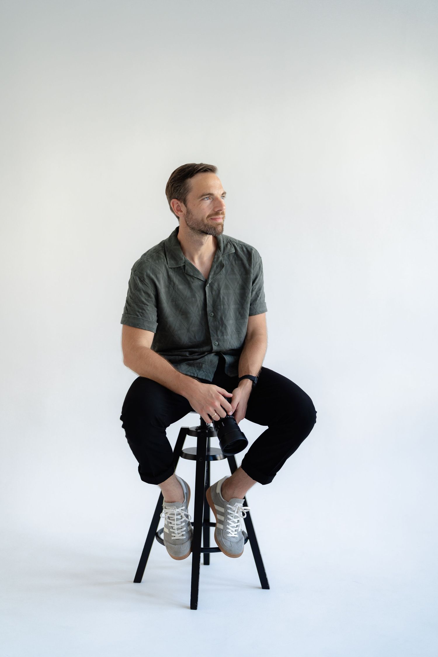 Professional portrait series showing casual poses on a black stool against a white background.