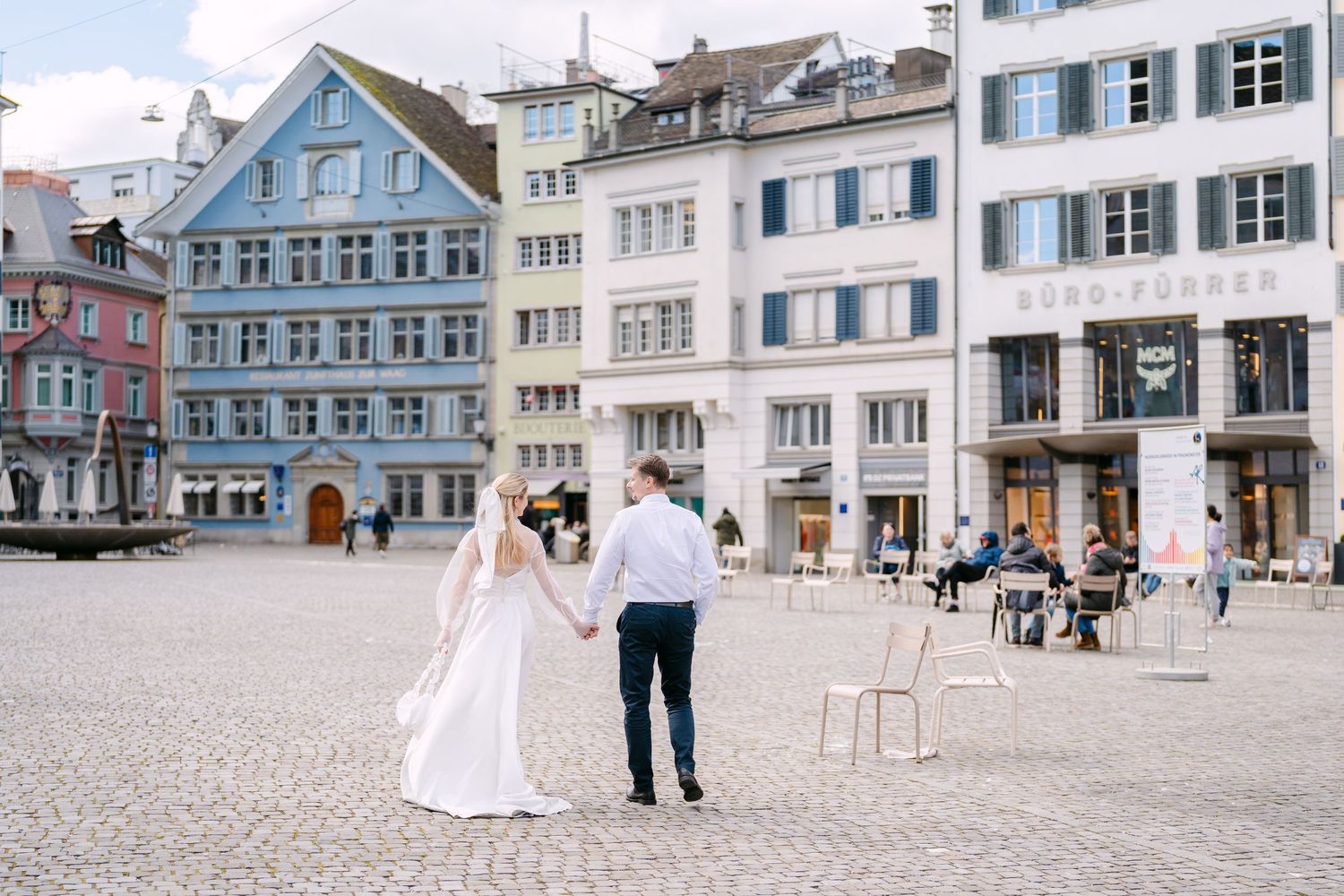 Couple walks through charming European town square with traditional architecture.