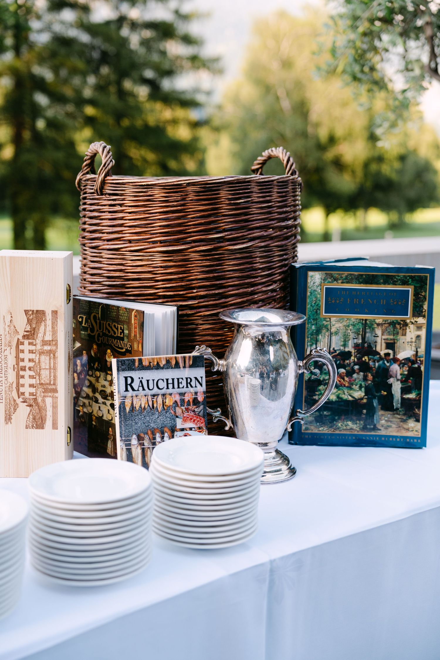 Table setting with wicker basket, plates and vintage books for outdoor event.