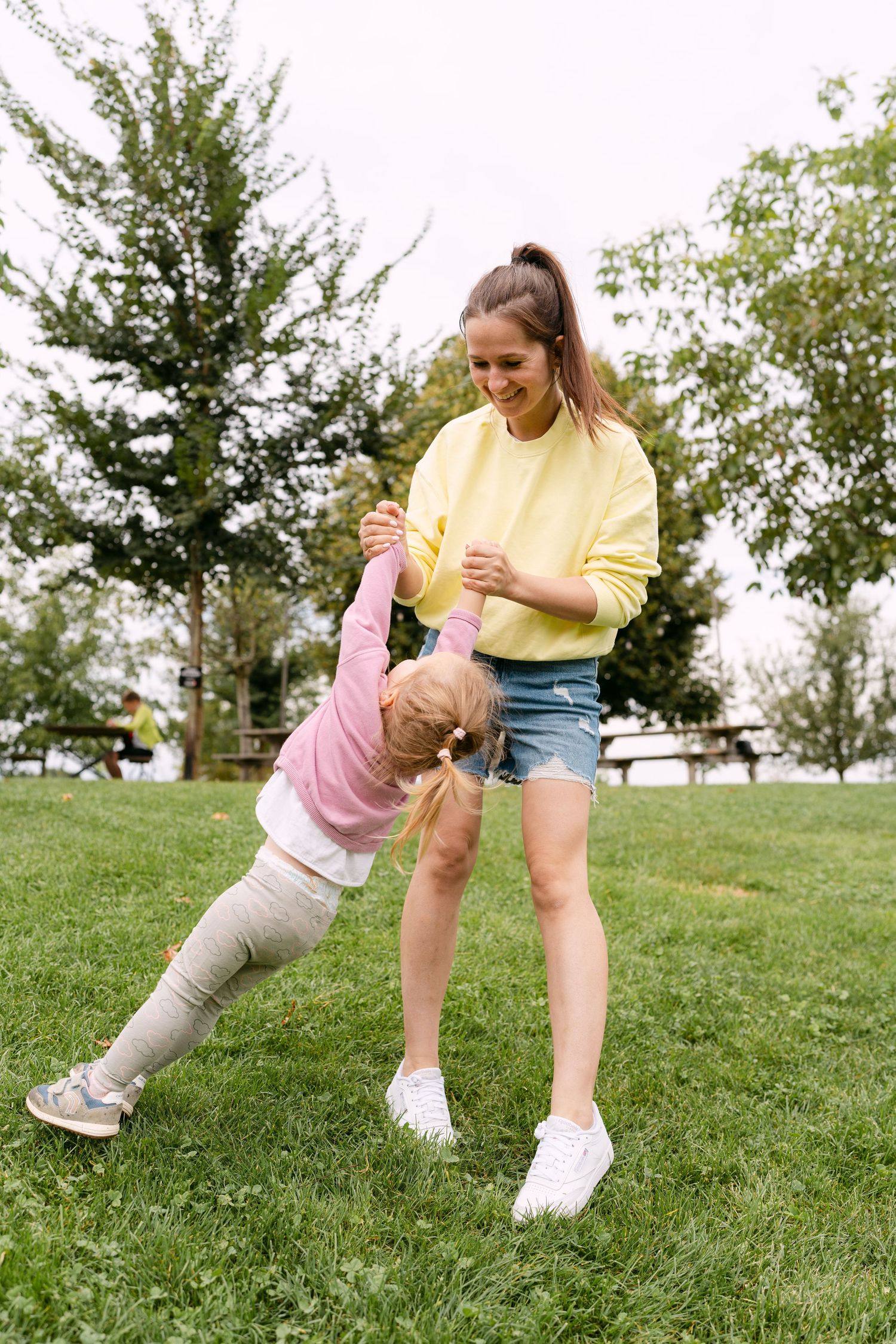 Playful interactions captured on a sunny grassy hillside with trees in the background.