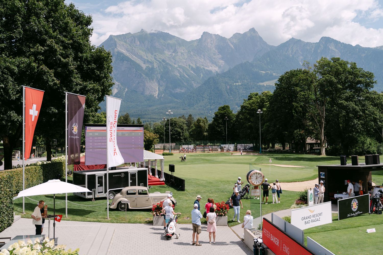 Outdoor event space with flags and mountains visible in background on sunny day.