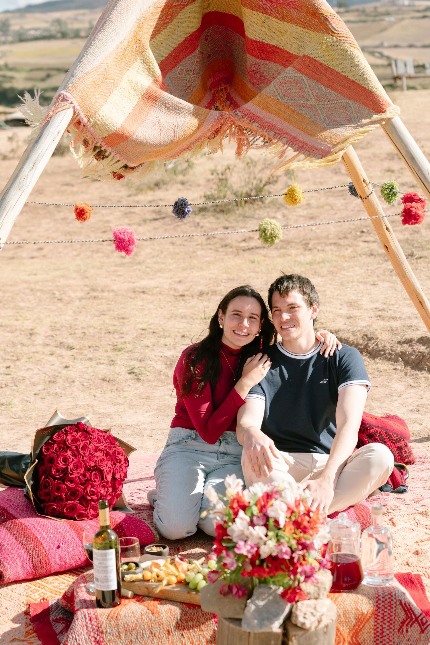 Desert picnic setup with fresh flowers, food spread, and mountain views.
