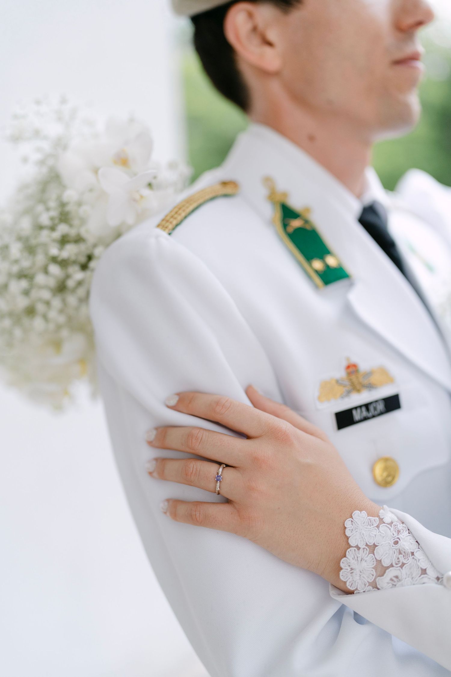 Close-up of military dress uniform details and wedding ring during ceremony.