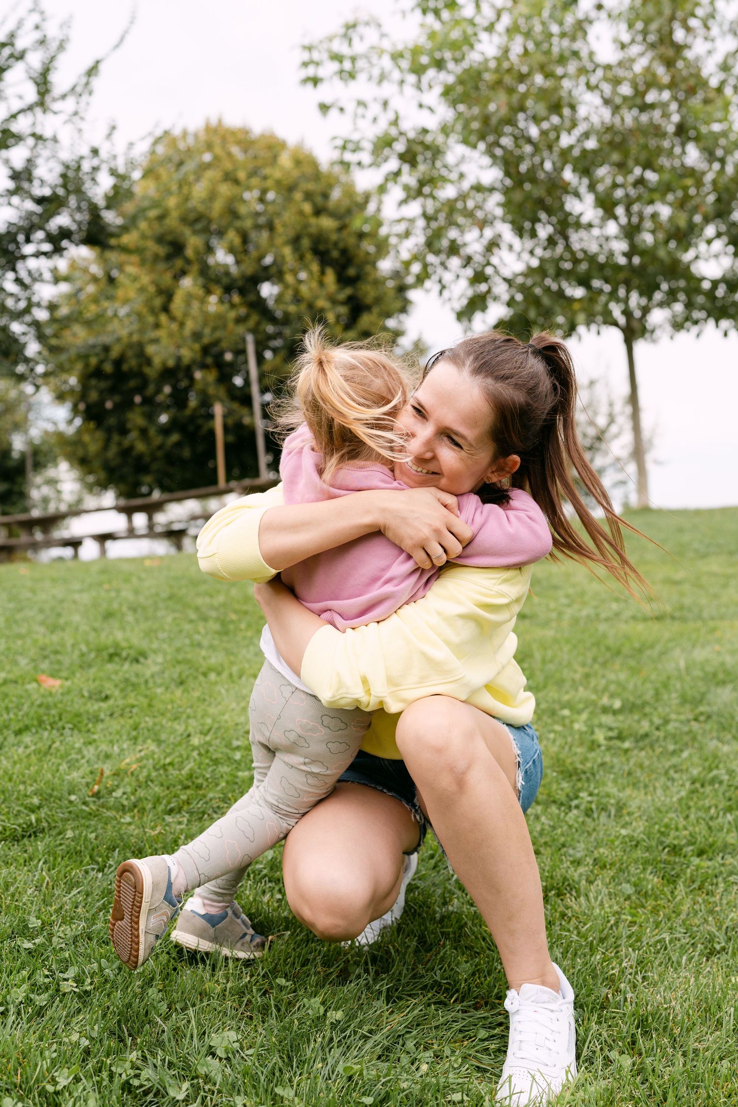 Joyful outdoor moments captured on a grassy hillside with warm embraces.