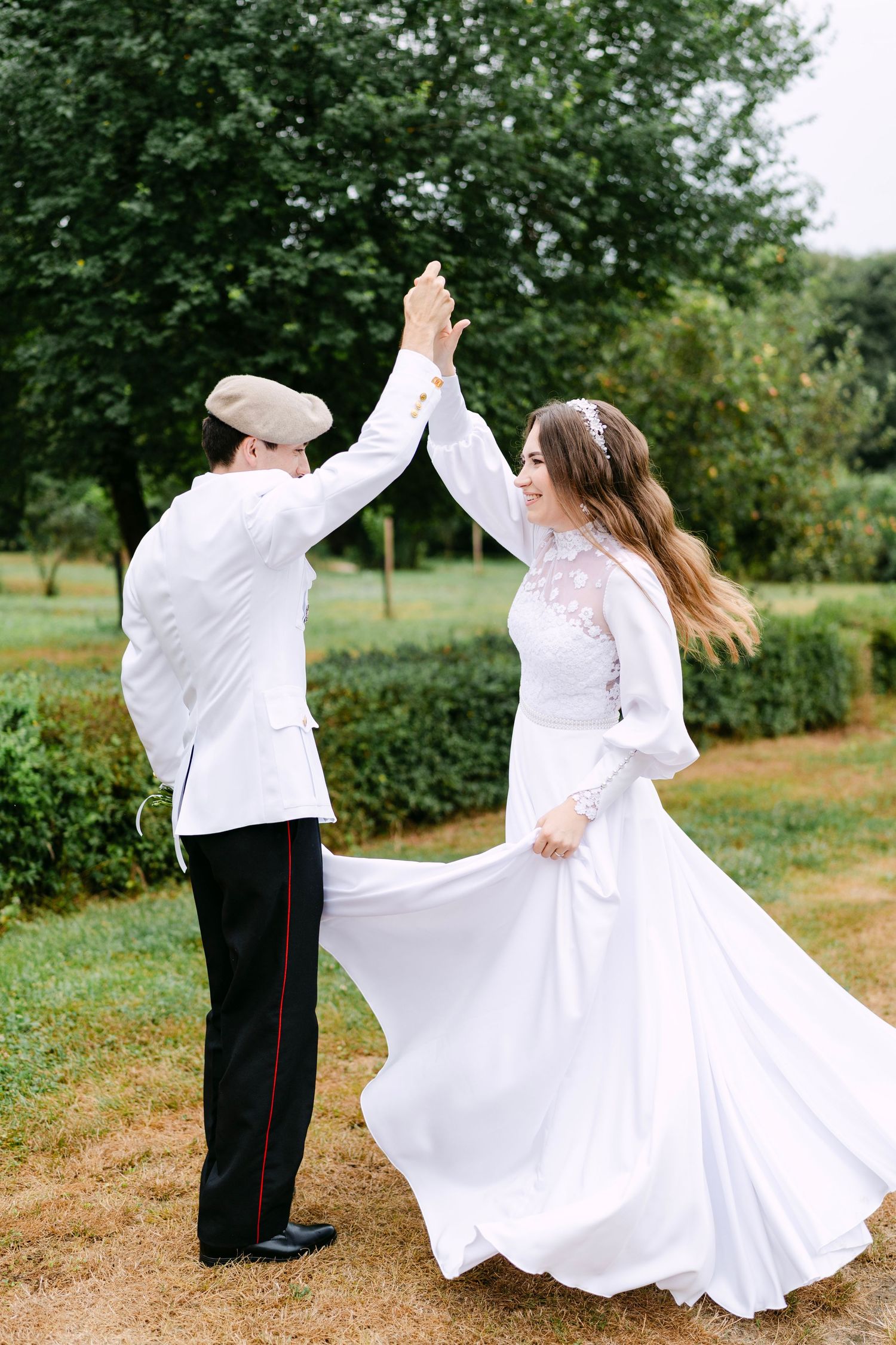Couple dances joyfully outdoors in white attire.
