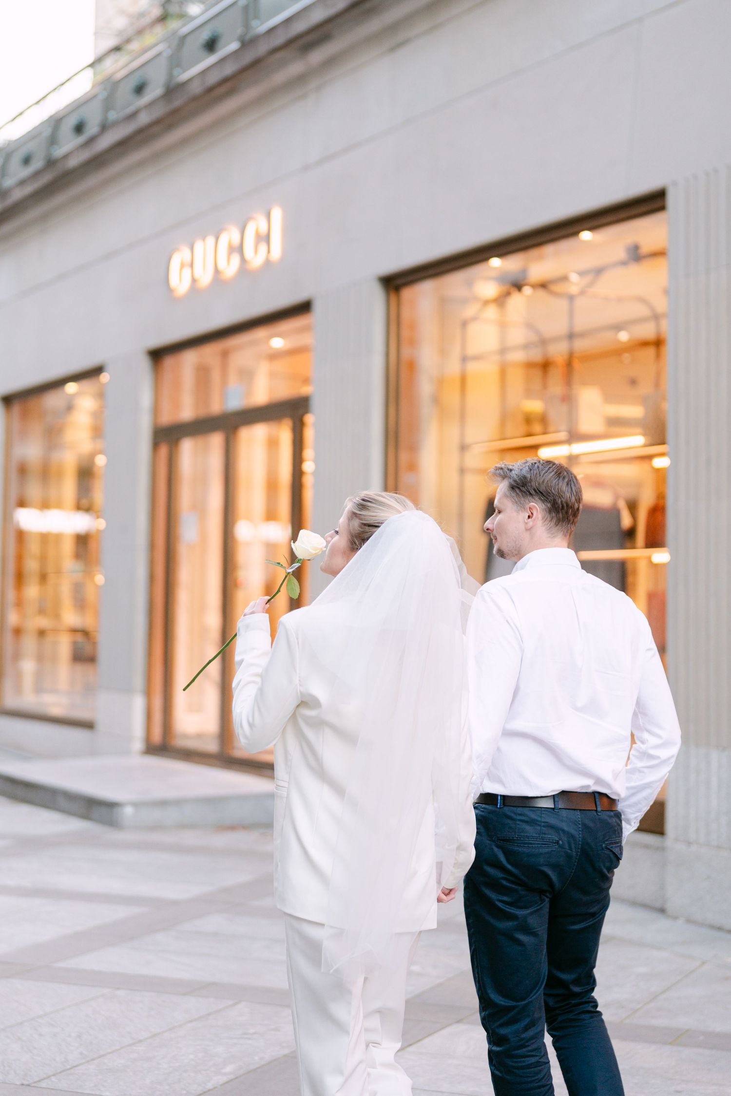 Elegant couple photographed outside luxury retail store with illuminated Gucci signage.
