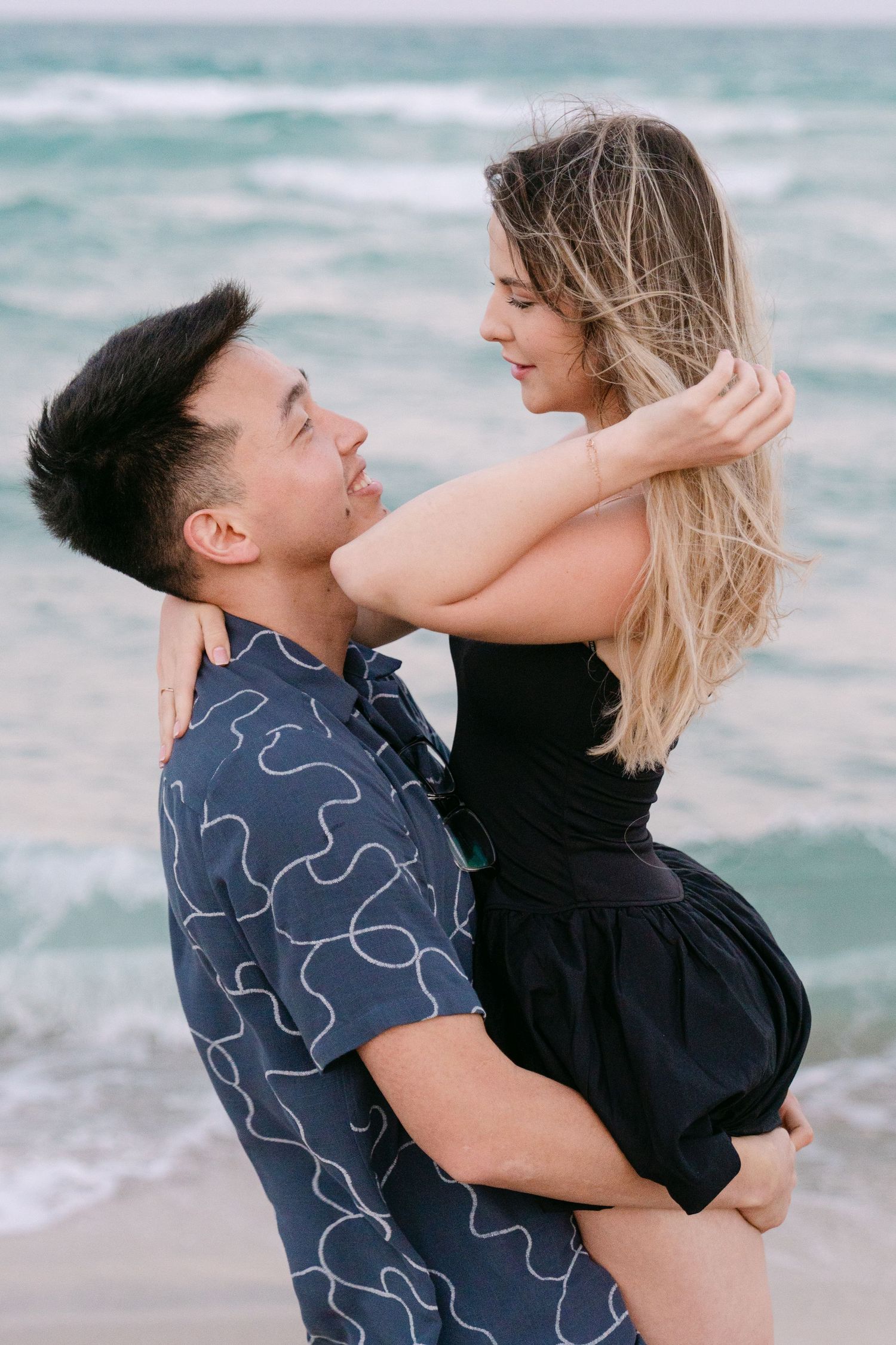 A romantic beach scene shows a couple embracing with ocean waves in the background.