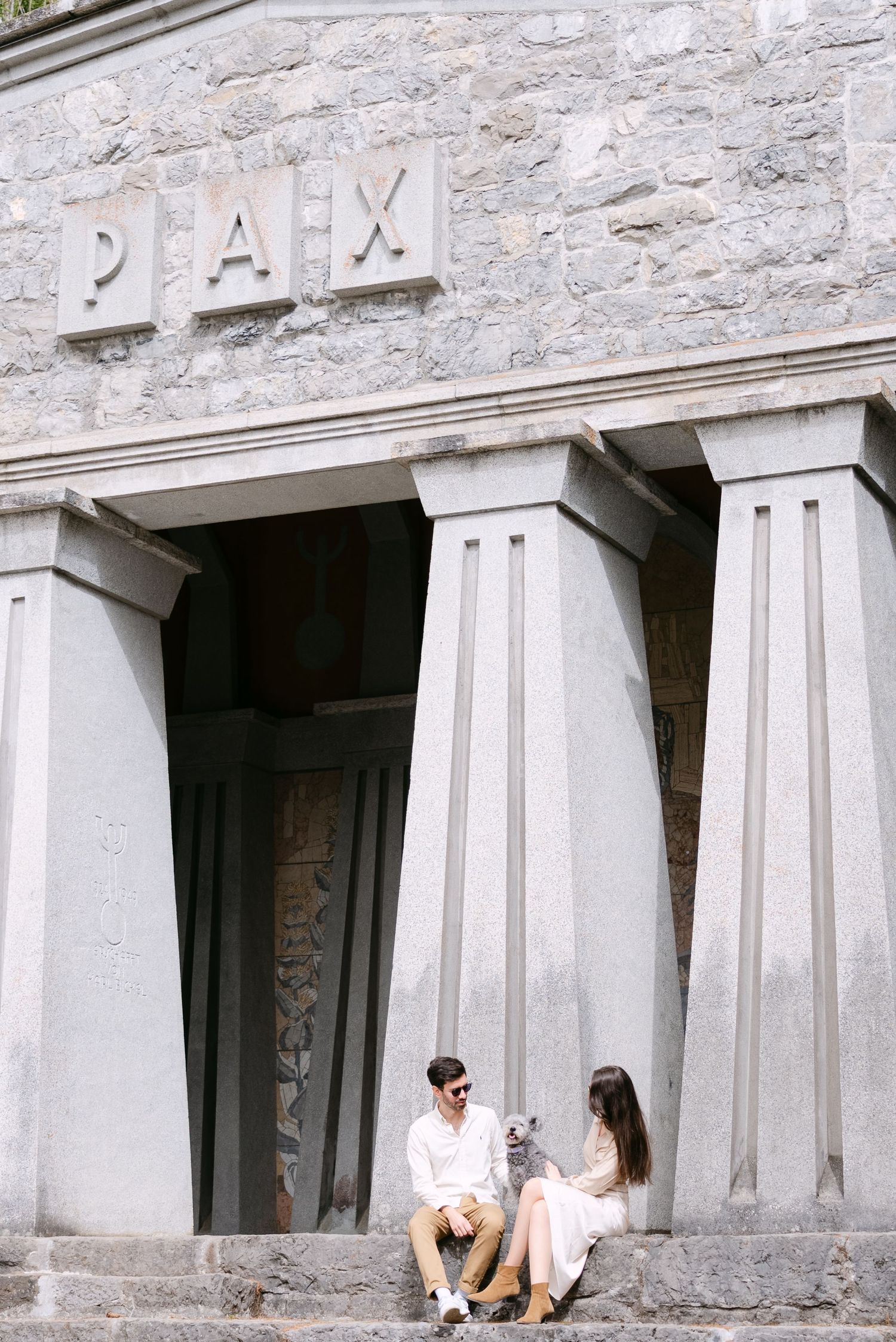 Stone architecture with white pillars and couple relaxing in casual outfits.