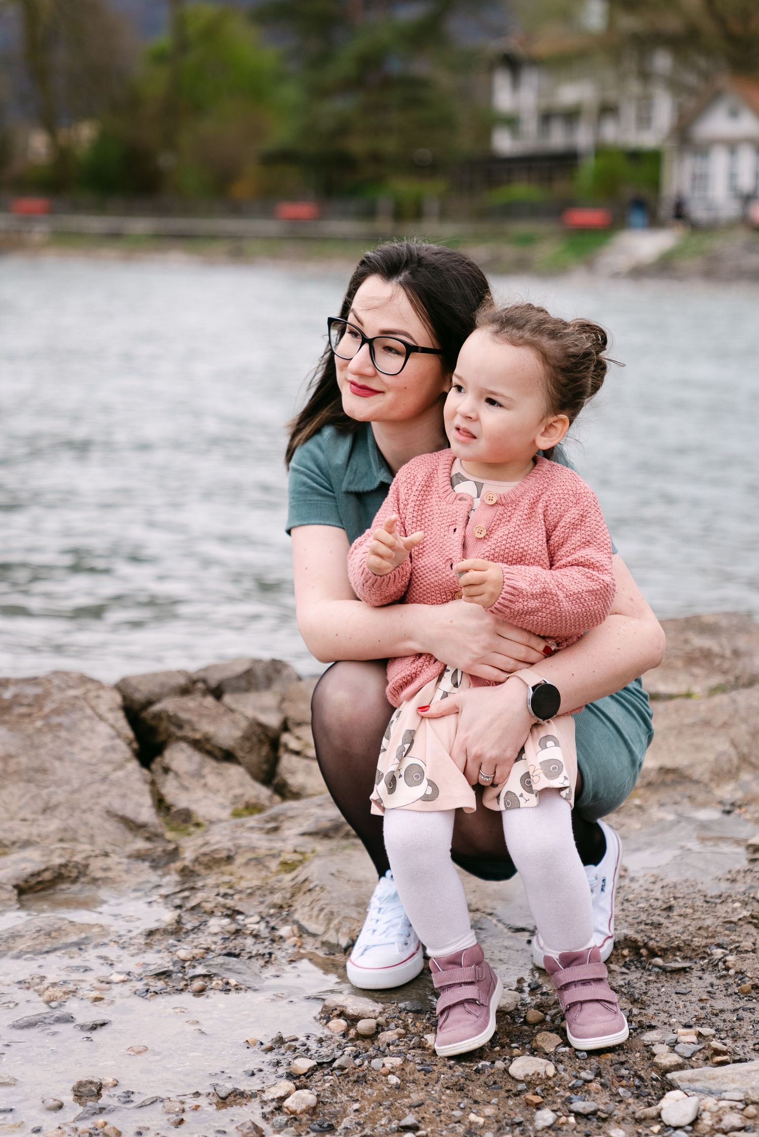 Tender moments shared on a rocky shoreline with water in the background.