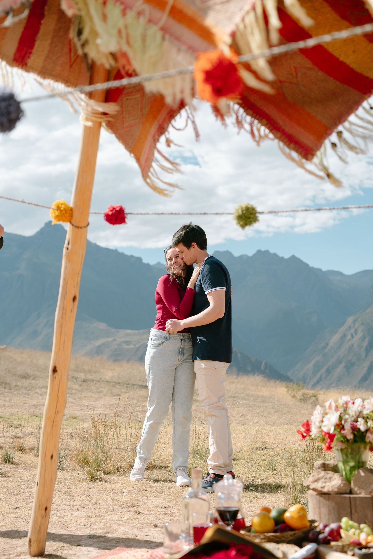 Romantic picnic setup in a desert landscape with colorful decorations and mountain backdrop.