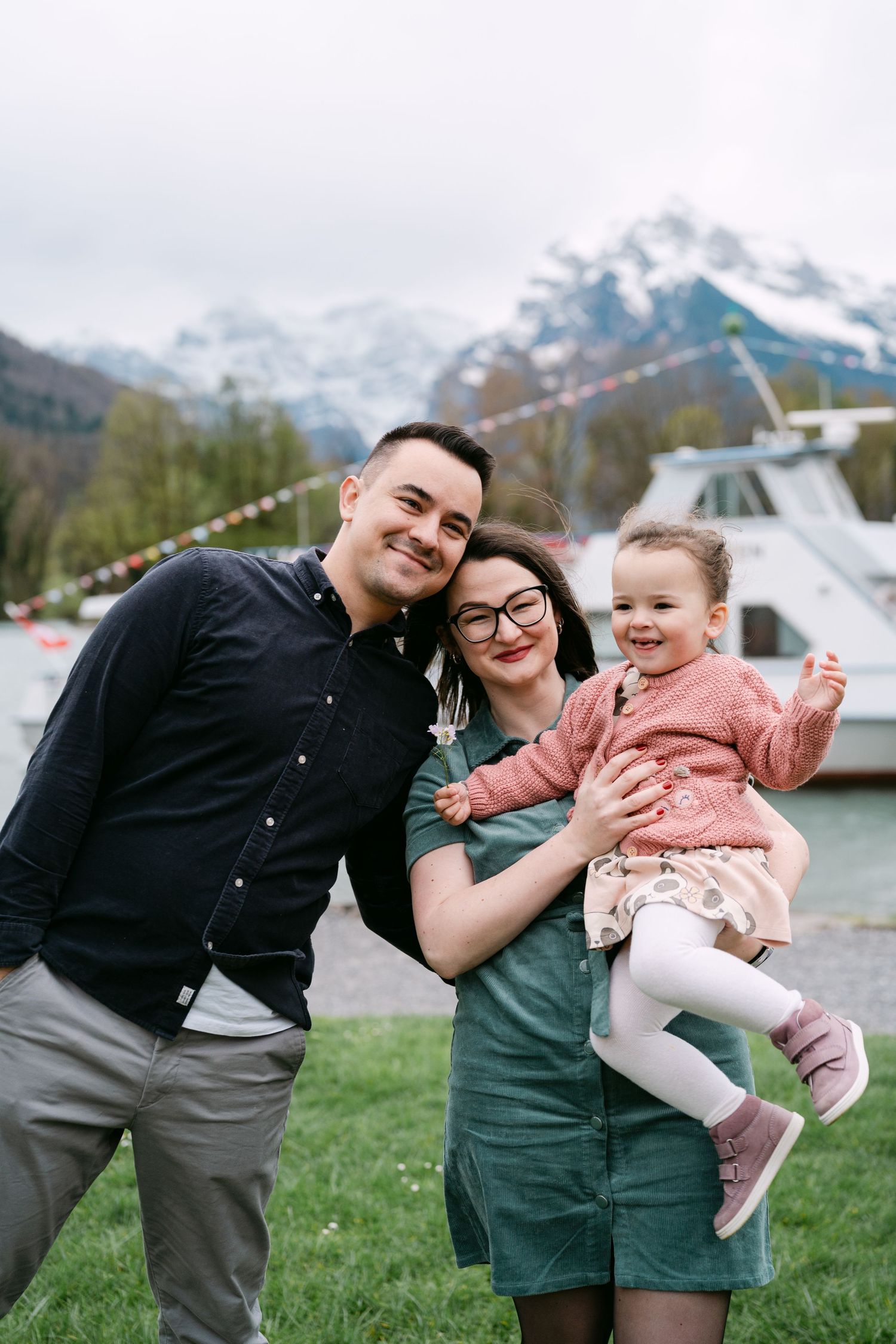 Family sharing laughs and embraces with mountains and lake in the background.