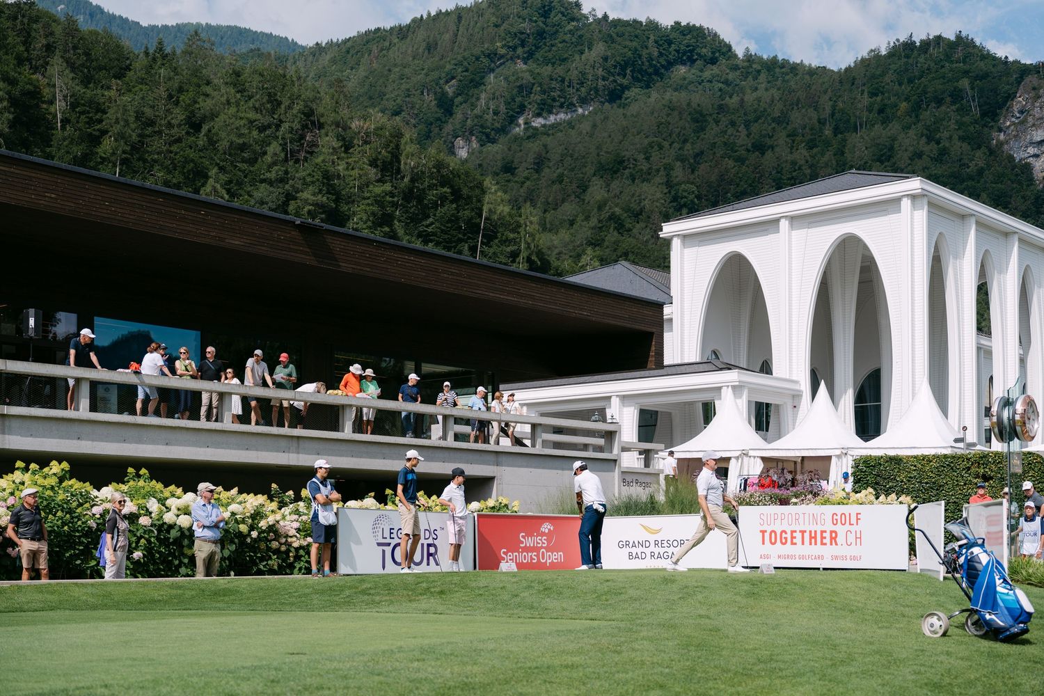 White clubhouse buildings nestled against mountain landscape at golf resort.