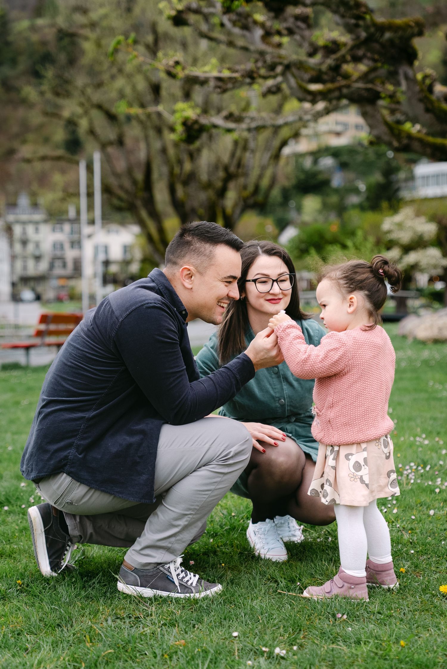 Family playing together on a grassy field with white flowers on a spring day.