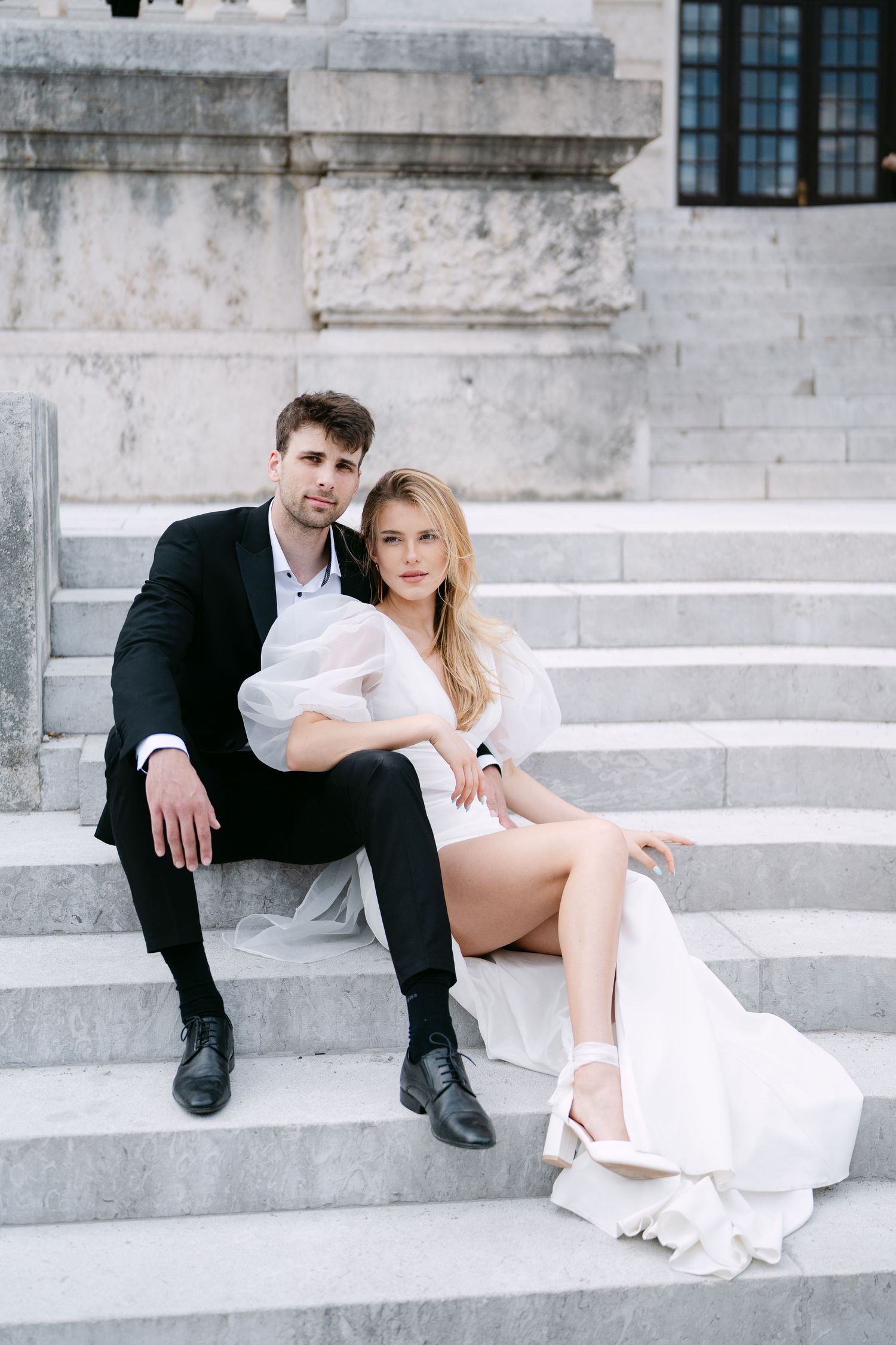Wedding couple sharing a tender moment while seated on grand marble steps.