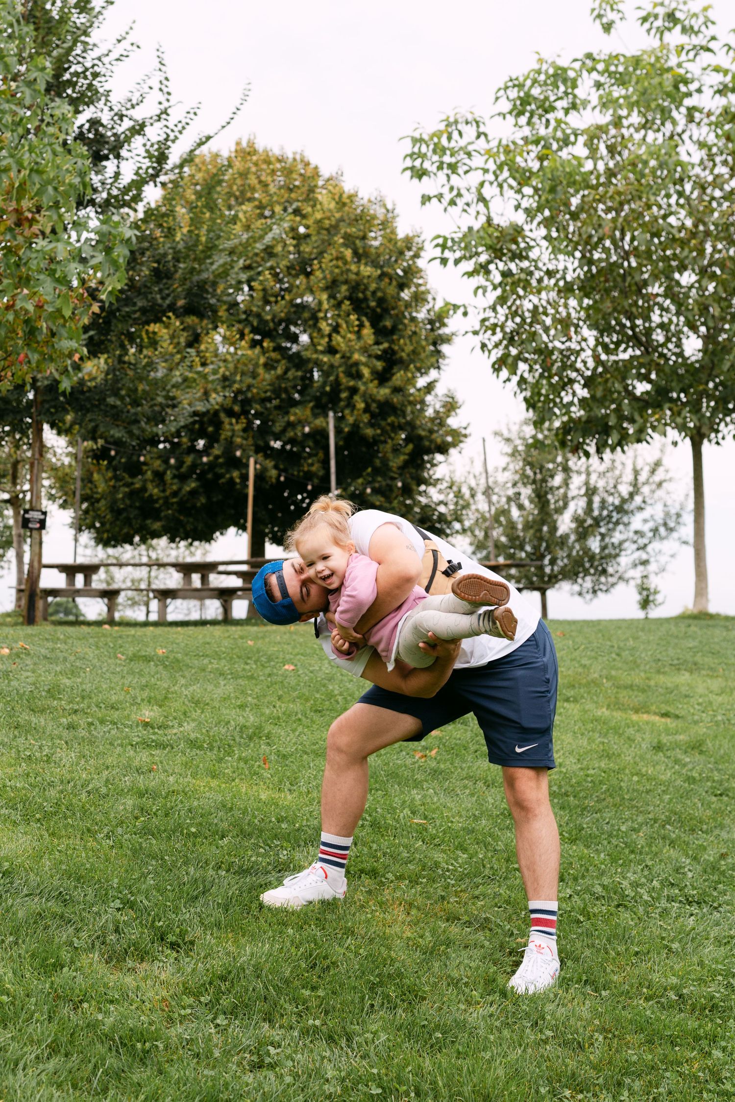 A series of photos showing someone in denim shorts and a pink top doing playful backbends on a grassy hill.
