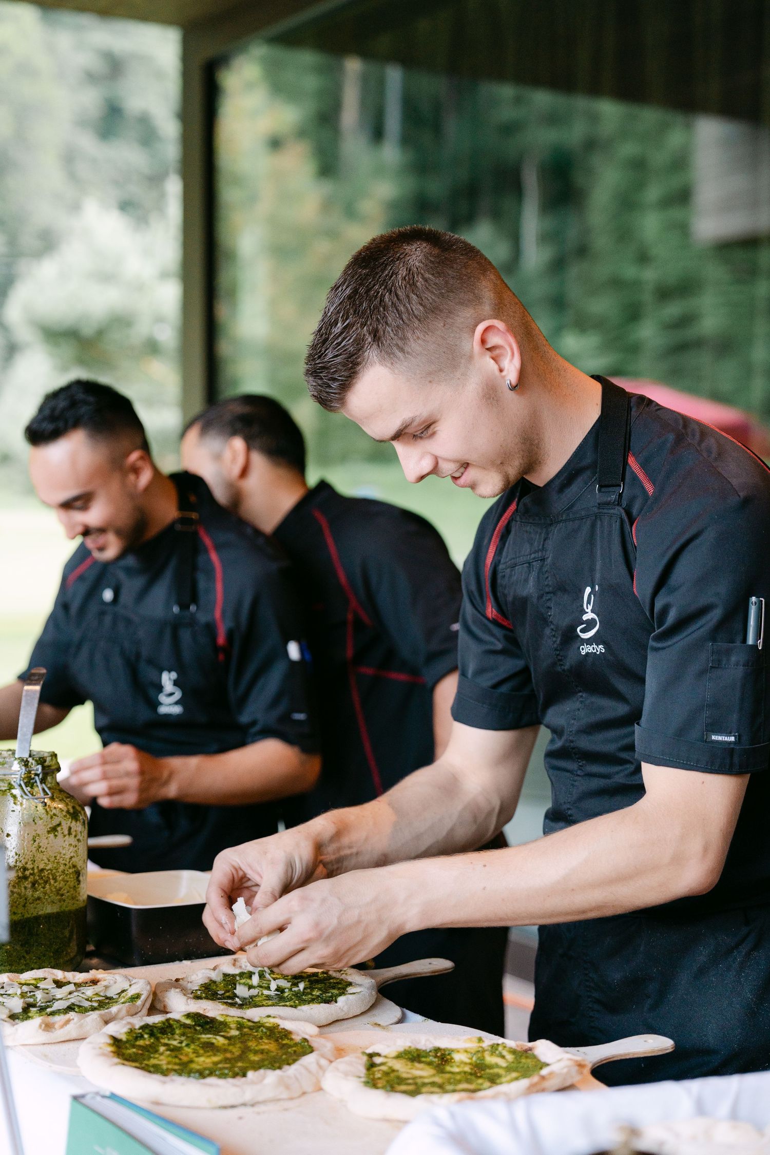 Professional chefs working in sync to prepare multiple flatbread dishes.