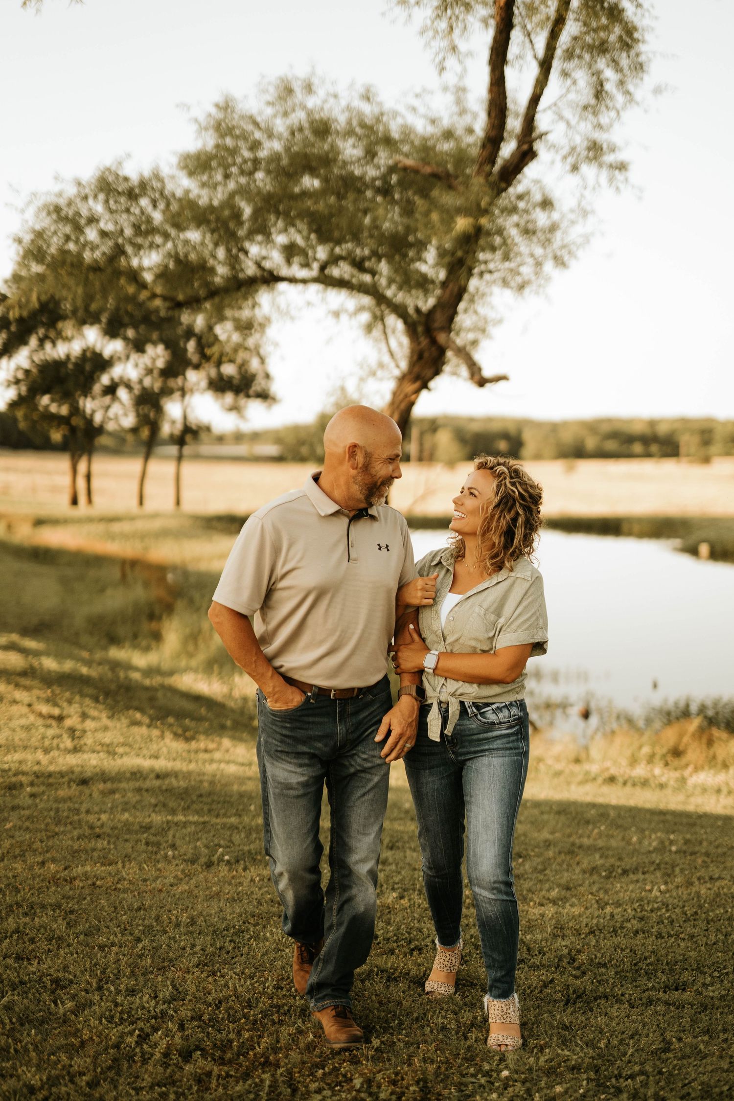 A couple takes a romantic walk by the lake during sunset.
