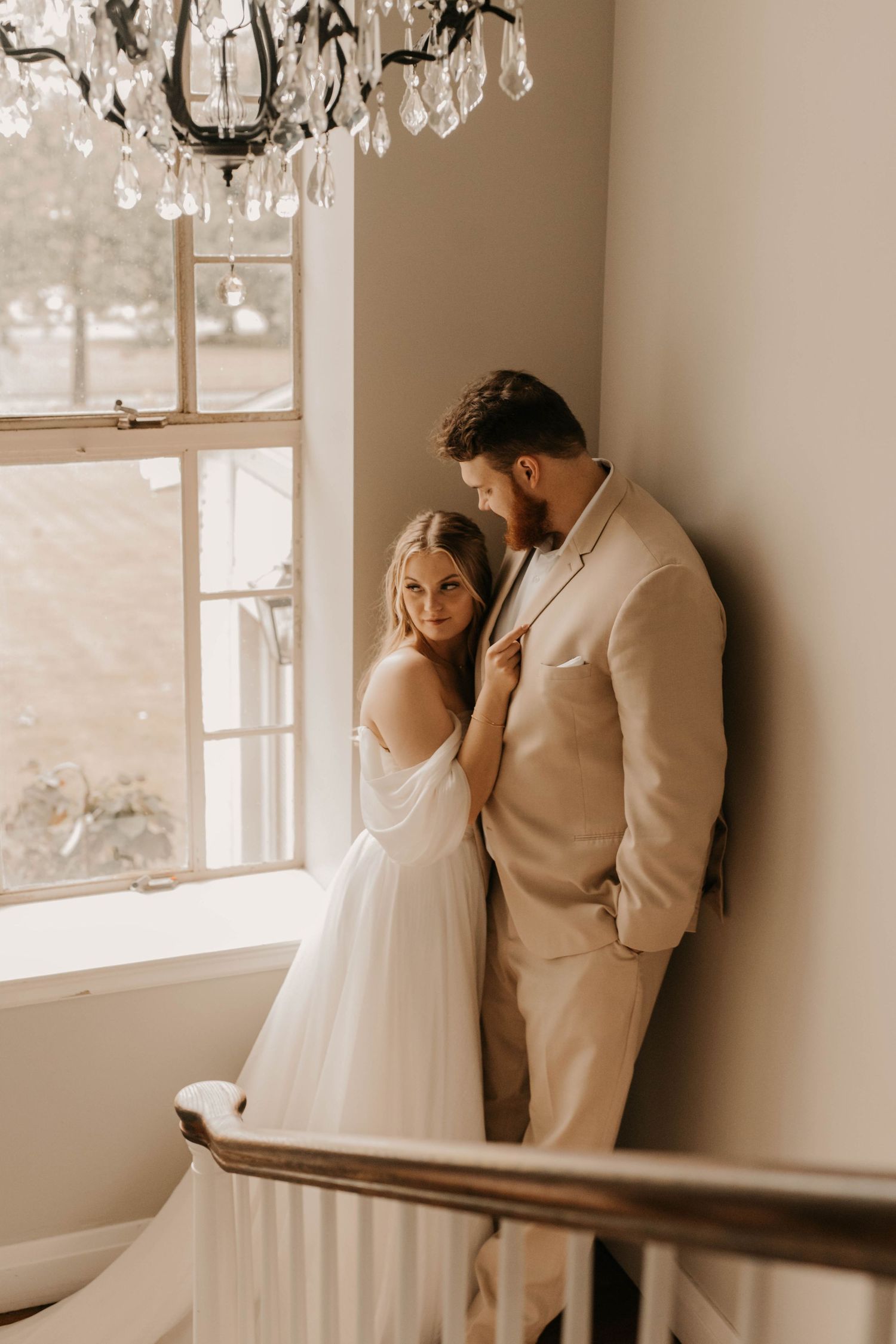 An intimate wedding portrait near a bright window with a crystal chandelier.