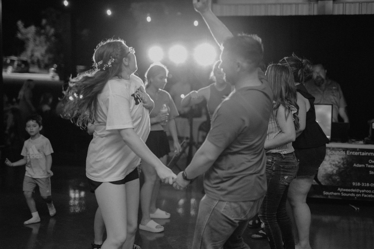 Wedding reception guests dancing under string lights at nighttime celebration.