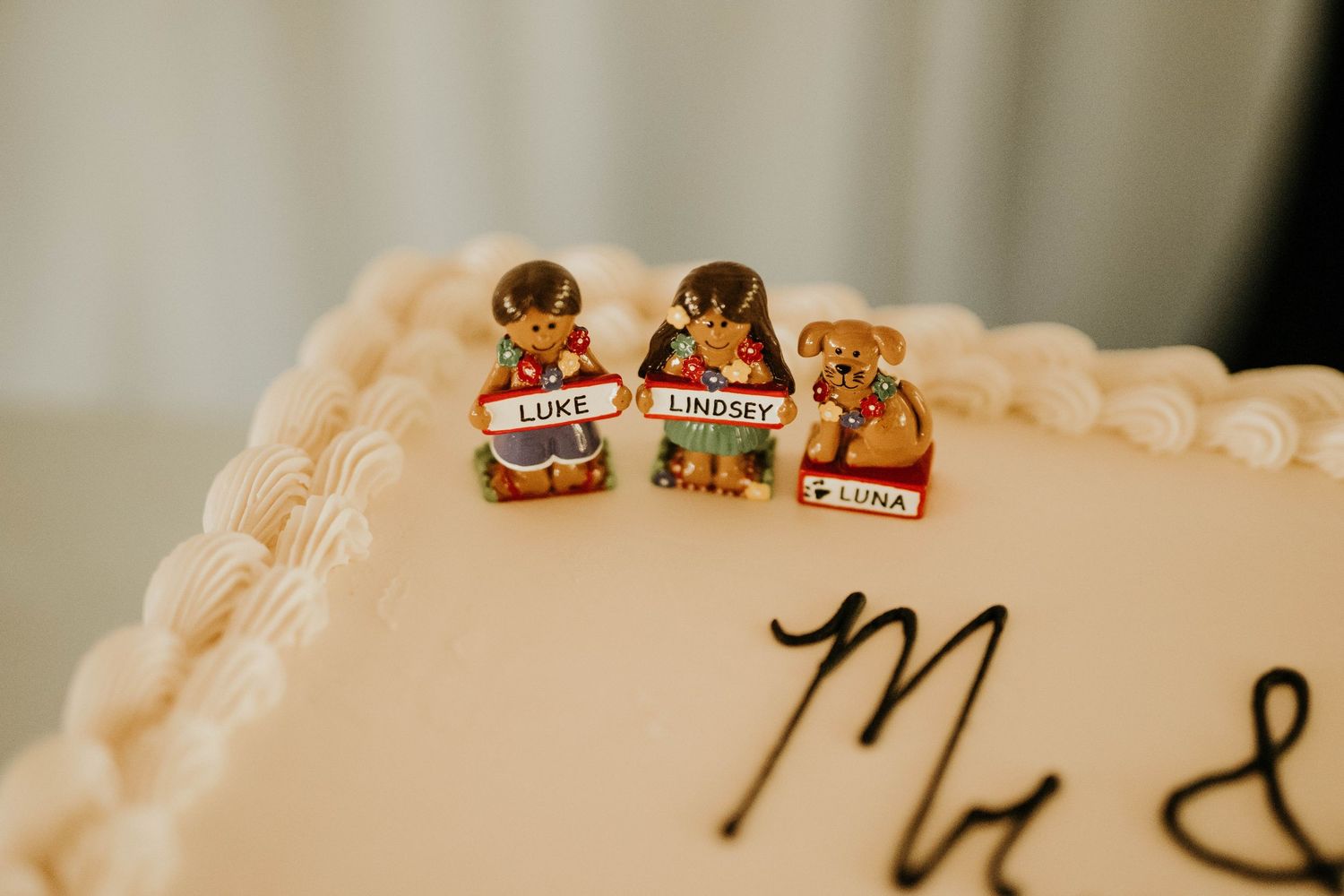 Cute miniature figurine cake toppers decorating white wedding cake with delicate piping.