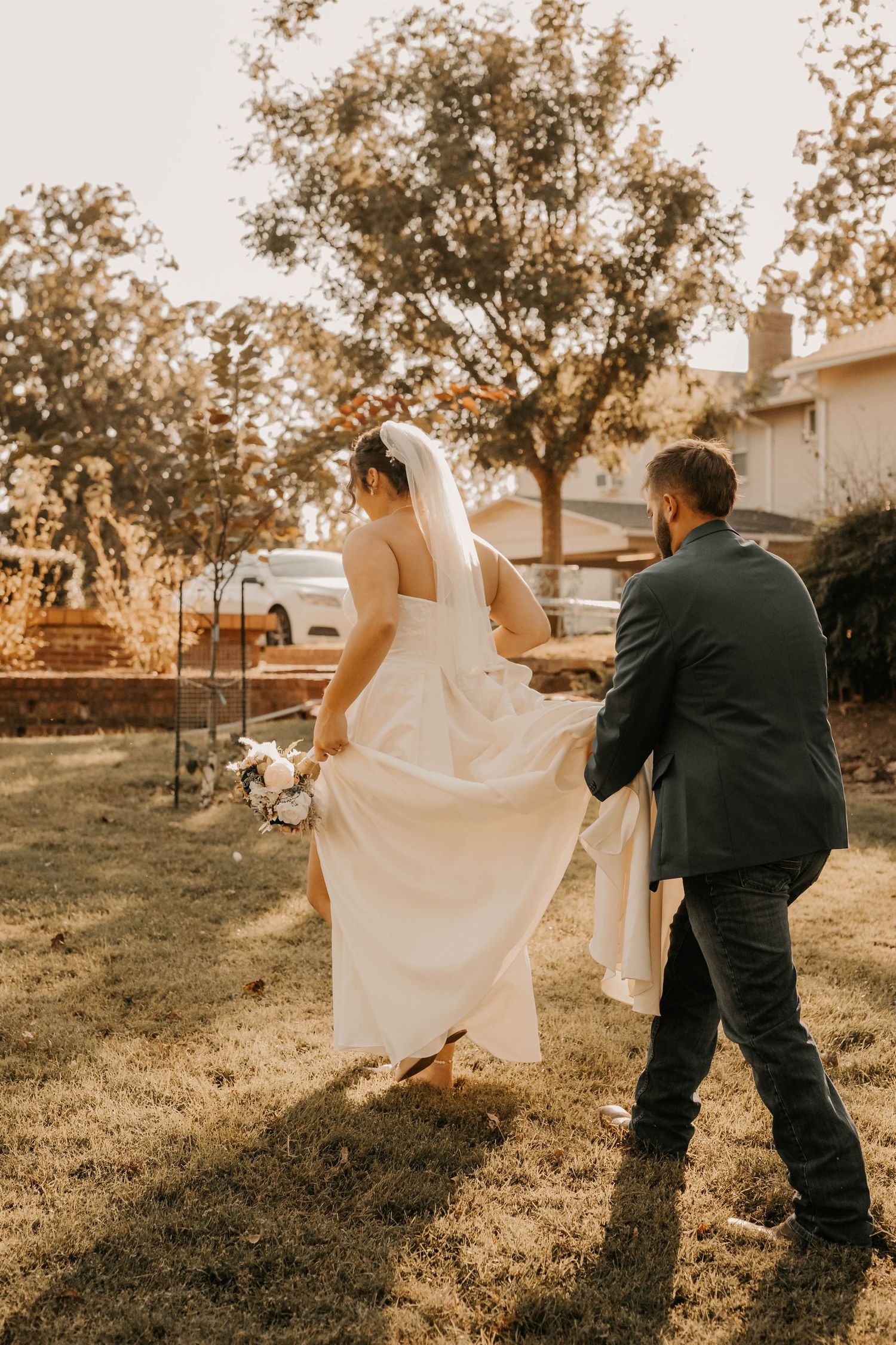 A couple walking outdoors with the bride's white dress flowing in the breeze.
