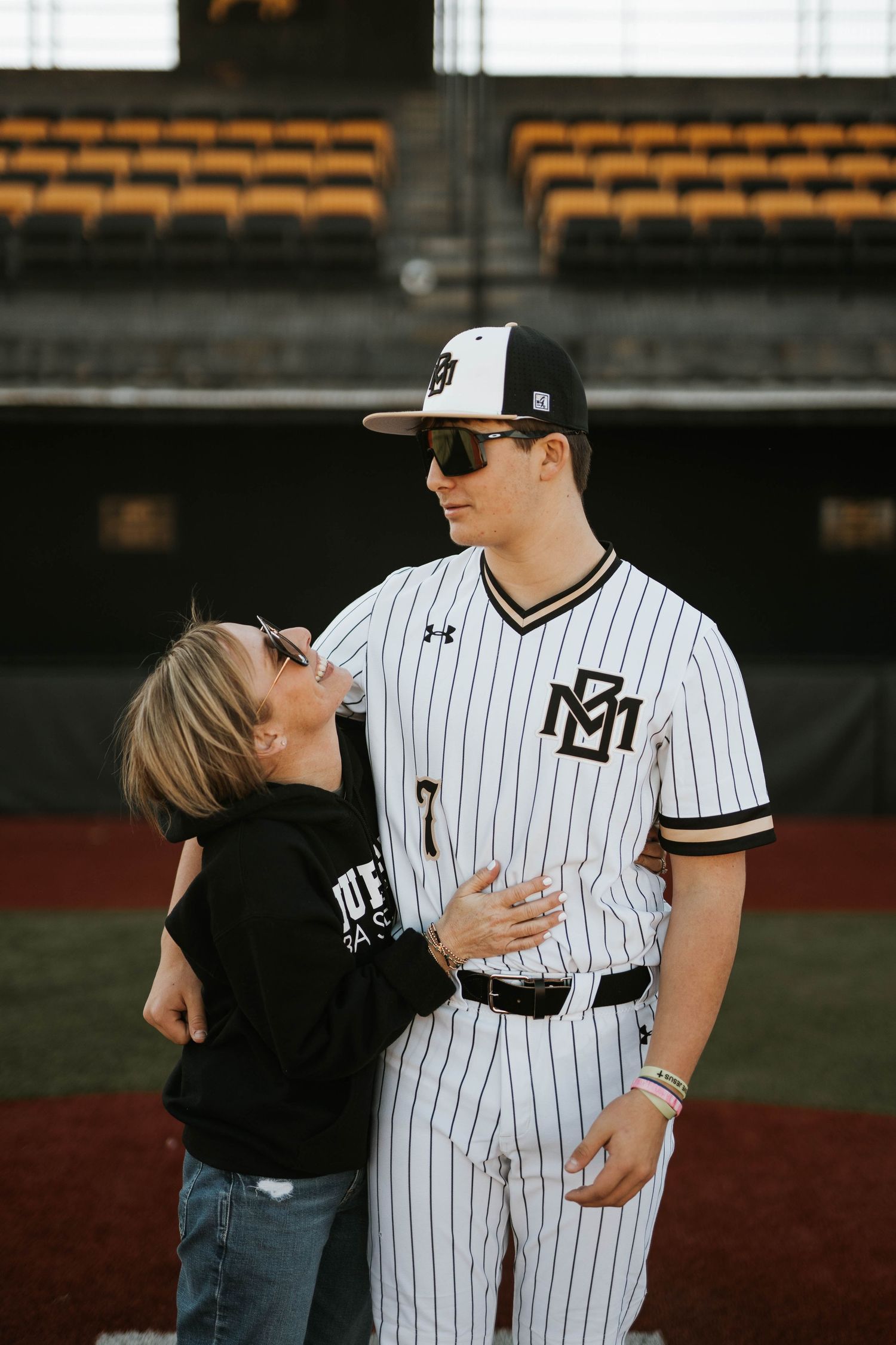Intimate moment between baseball player in striped uniform and supporter on baseball field.