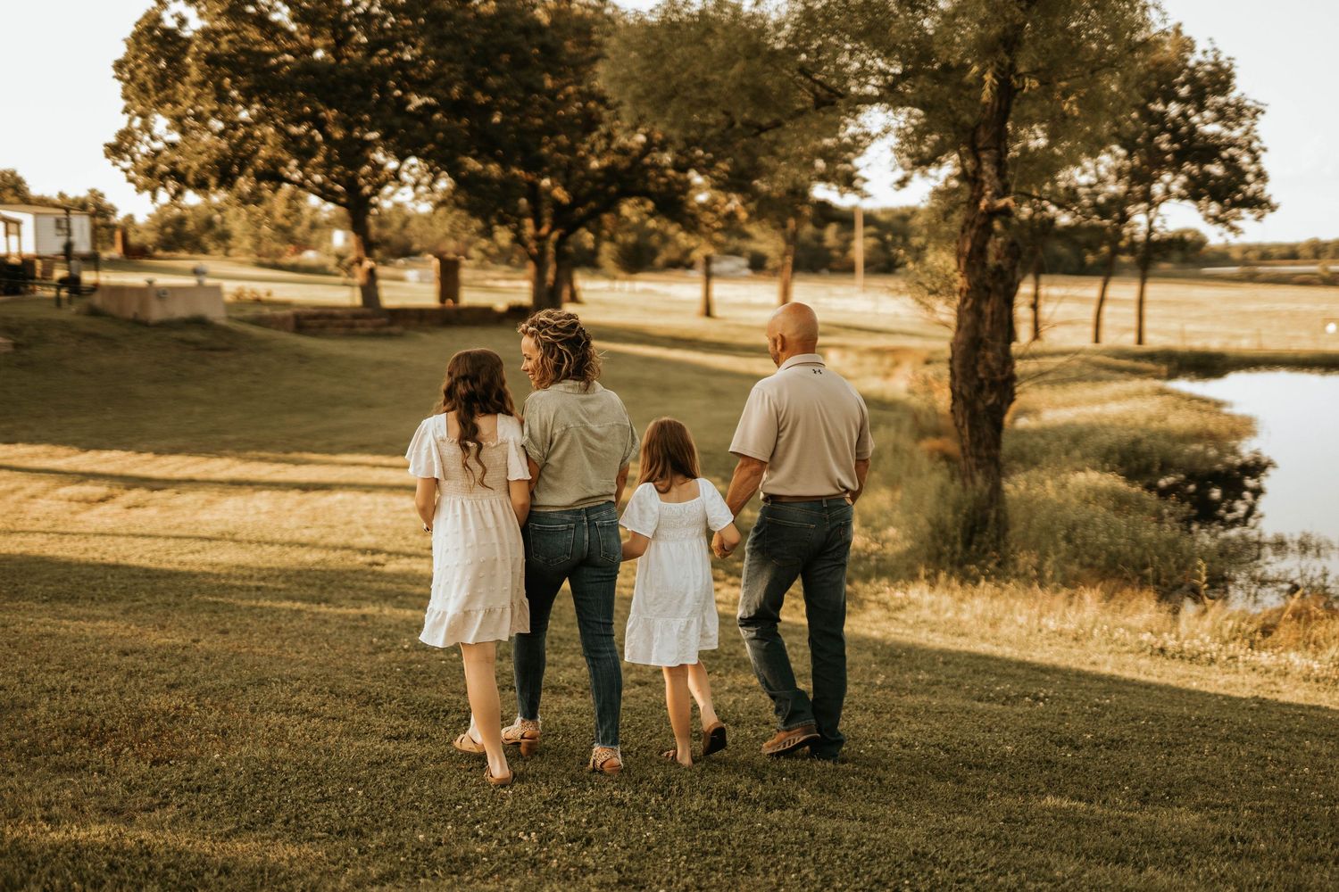 A family walks together along a serene lakeside path during golden hour.