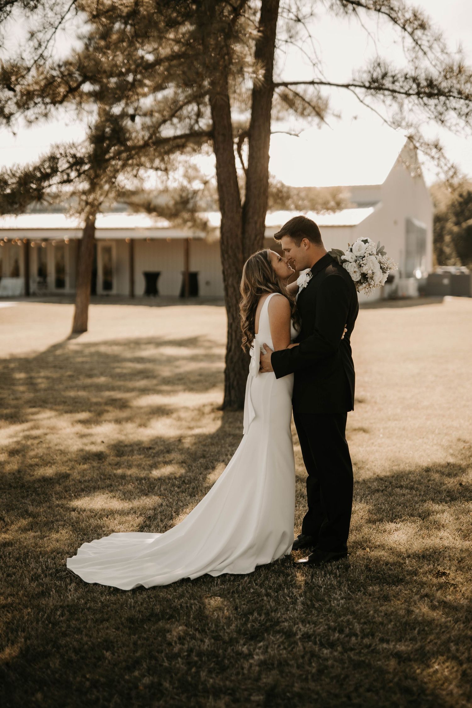Newlyweds share an intimate moment under pine trees during their outdoor wedding photoshoot.
