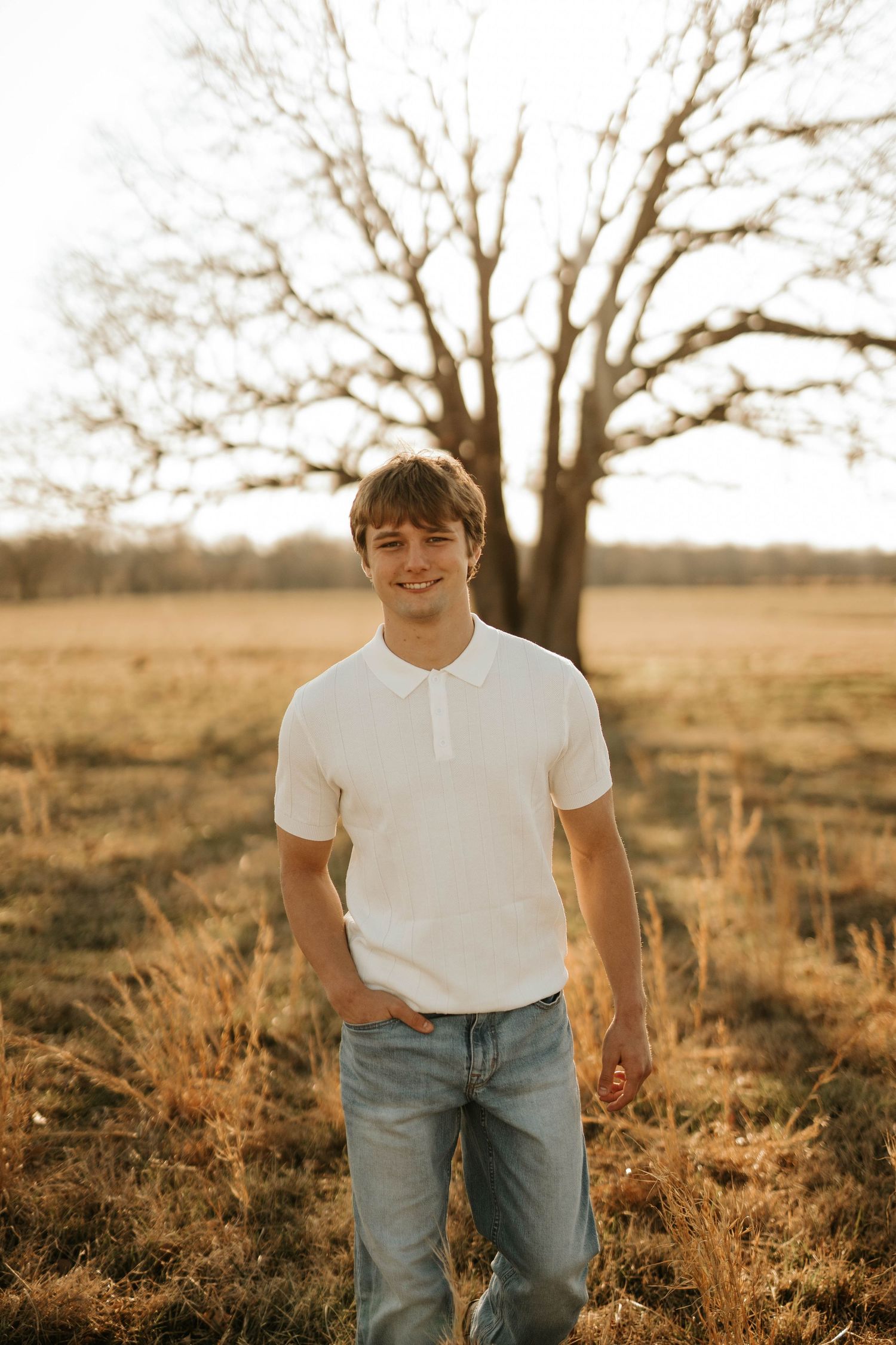 Golden hour portrait in a field with bare trees in the background.