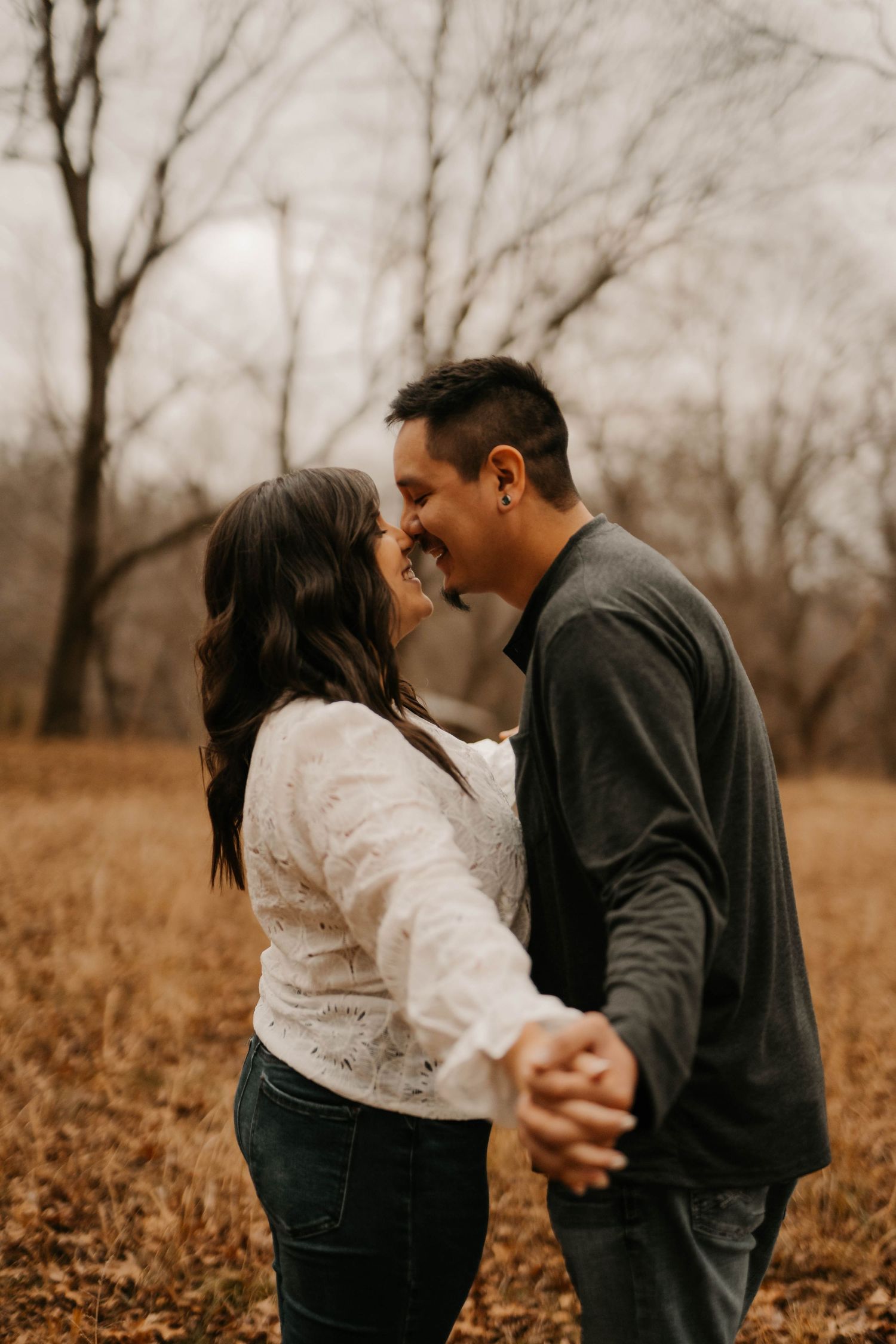 Romantic autumn engagement photo of couple embracing and sharing intimate moment in field.