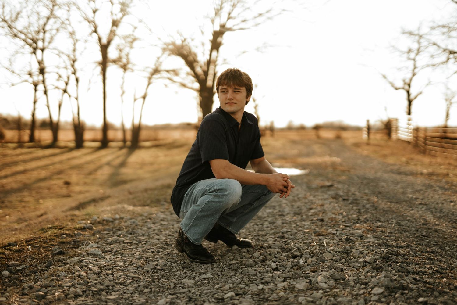Outdoor autumn portrait against a rustic backdrop with bare trees.