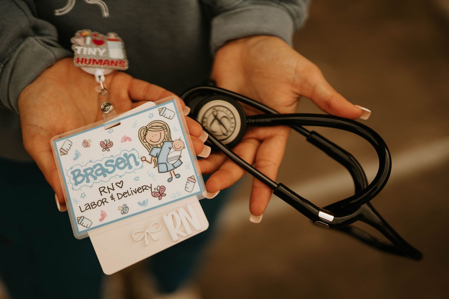 Close-up of hands holding medical ID badge and stethoscope.