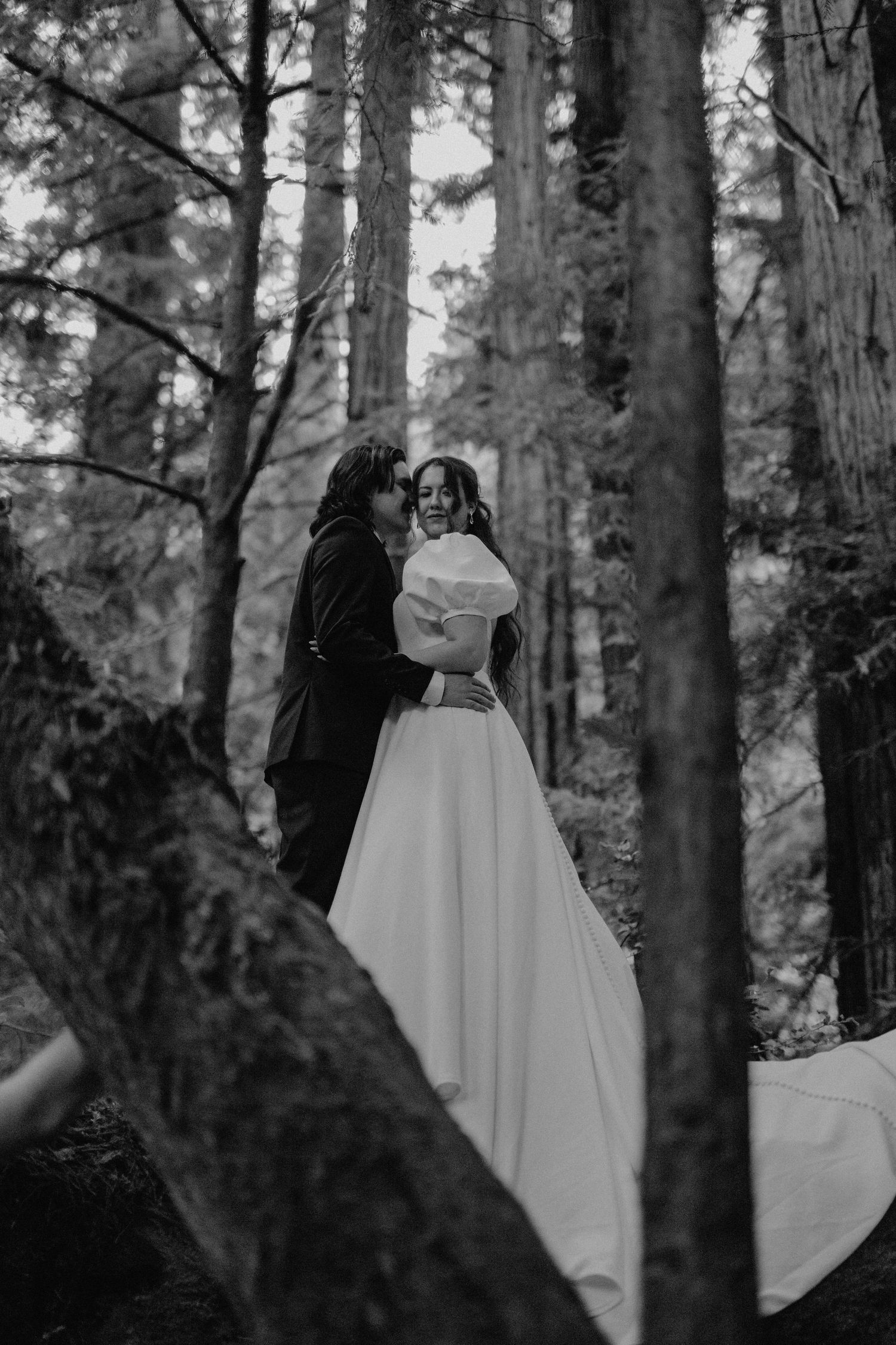 Intimate black and white wedding portrait showcasing tender moments in a forest setting.
