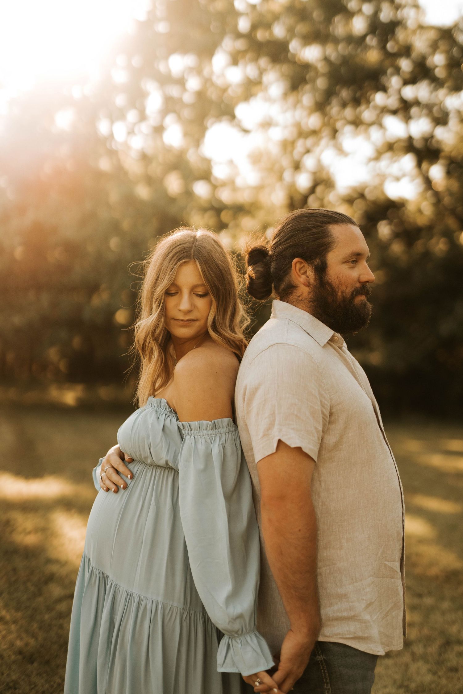 Romantic maternity portraits at sunset with soft backlighting and a light blue flowy dress.