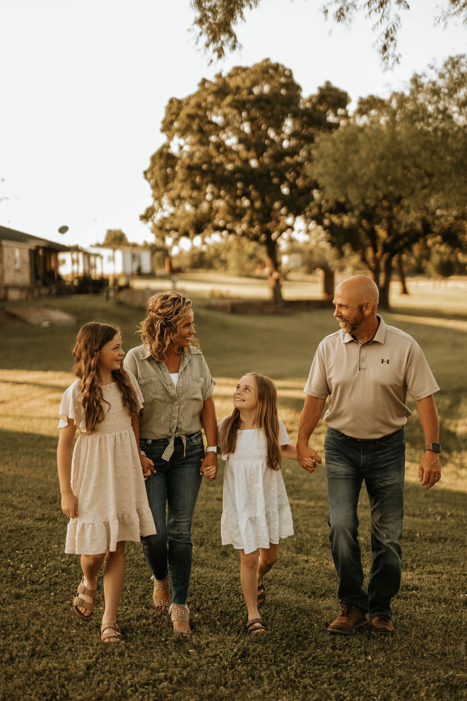 Family walking together through grassy field during golden hour portrait session.