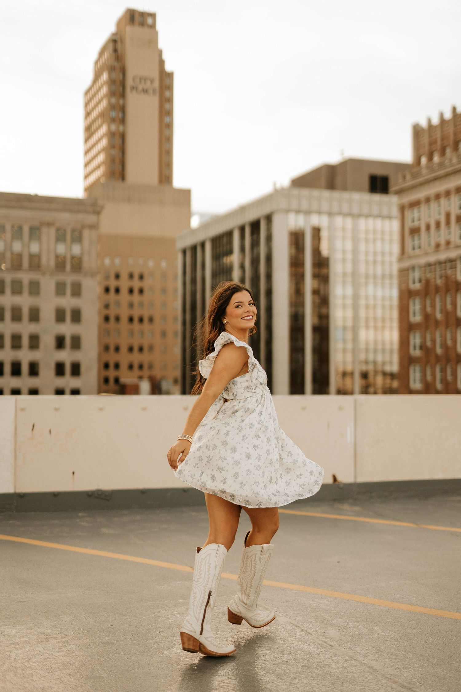 Twirling floral dress against urban architecture at sunset.