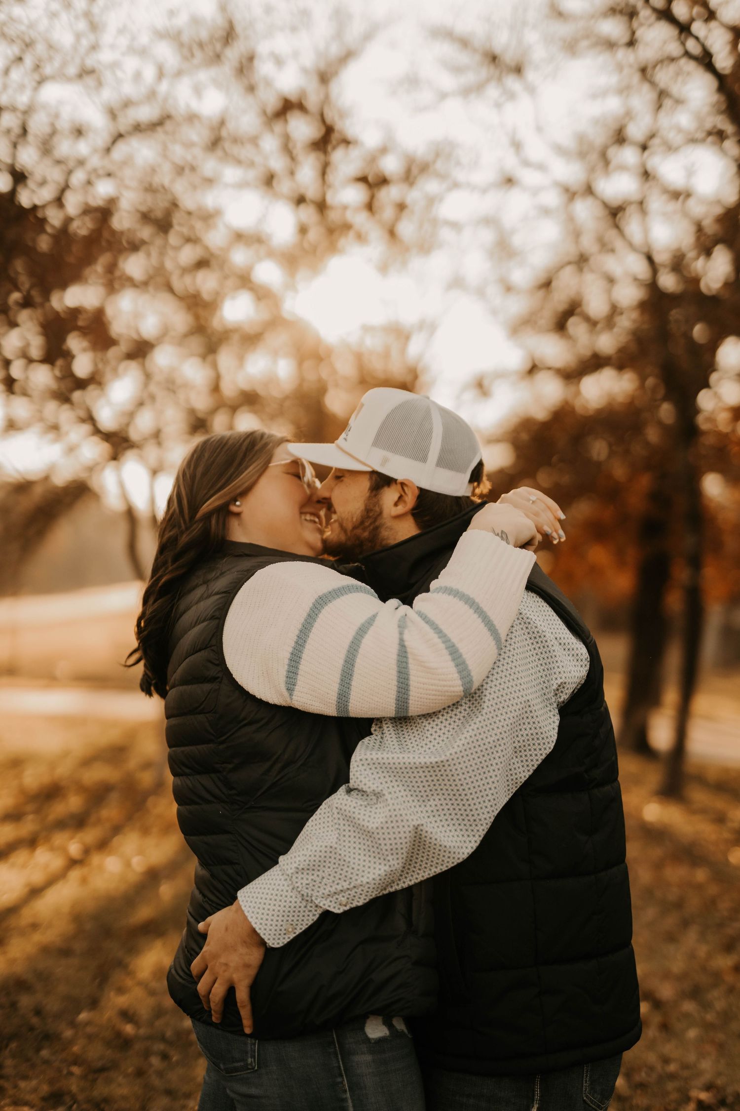 Intimate couple embrace during golden hour with autumn bokeh background.